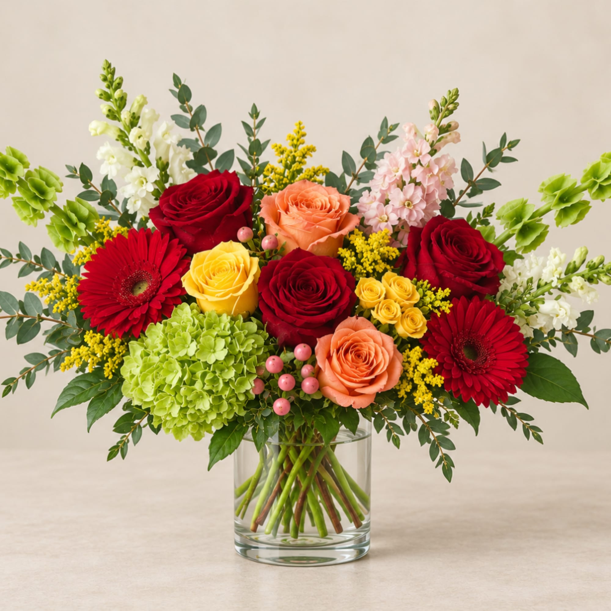 Mixed bouquet of roses, gerbera daisies, and hydrangea in a clear glass vase
