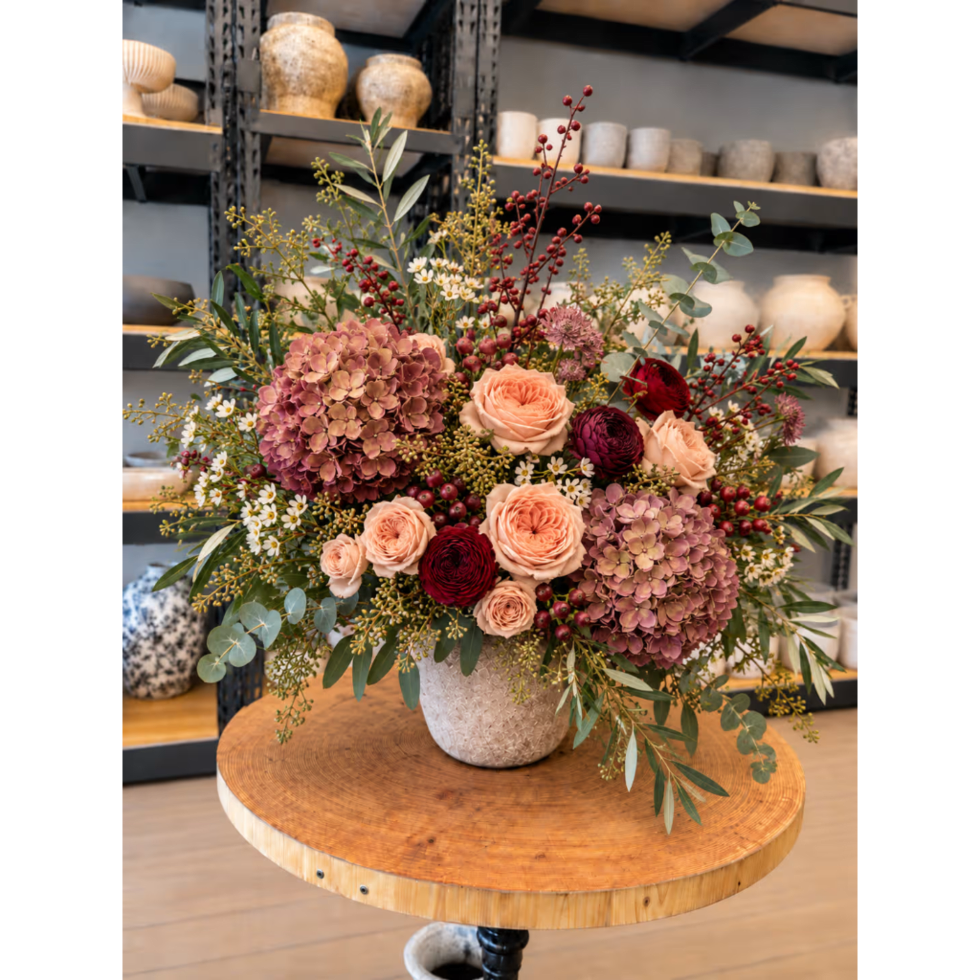 Large mixed floral arrangement in a textured vase on a round table