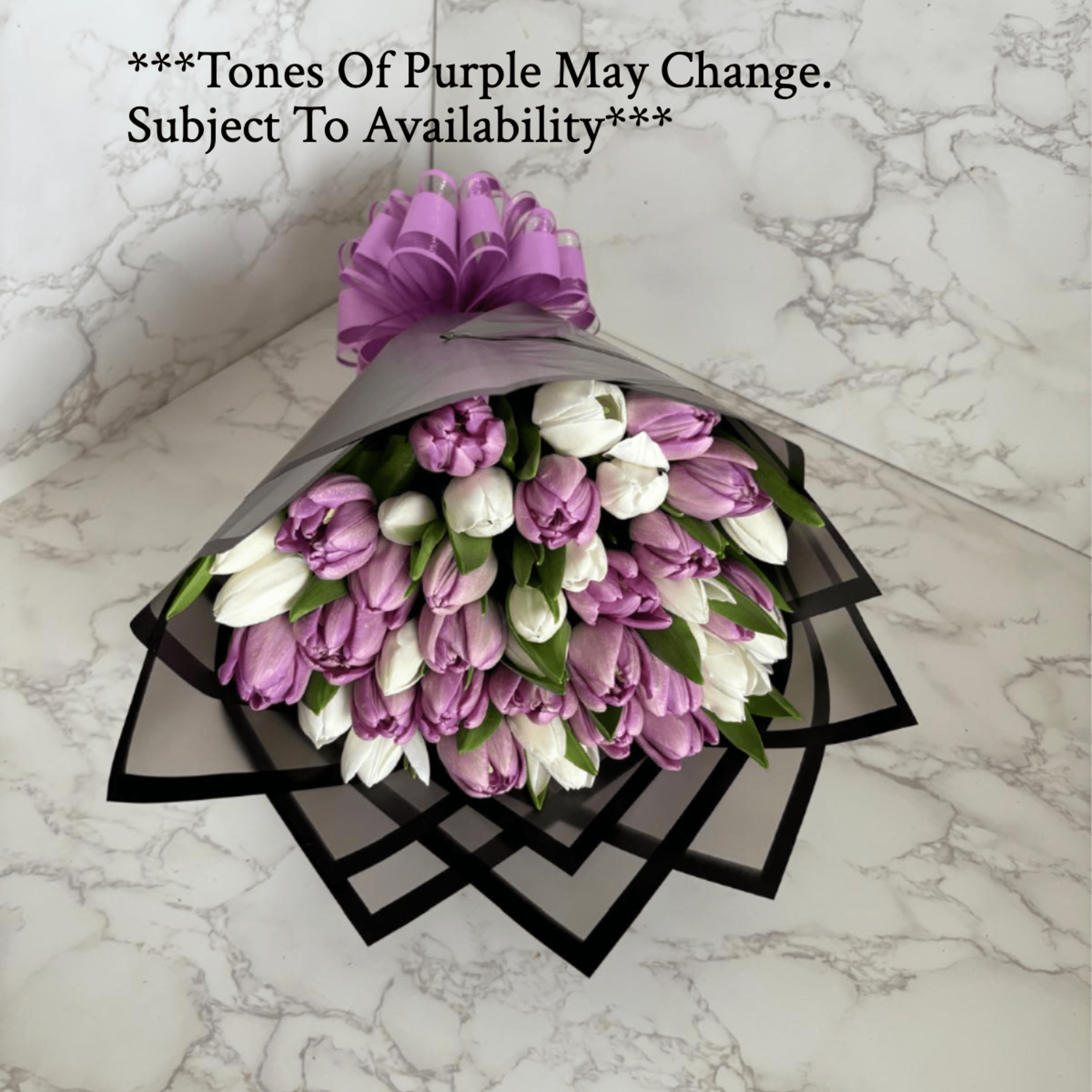 Bouquet of purple and white tulips wrapped in black paper with a purple bow