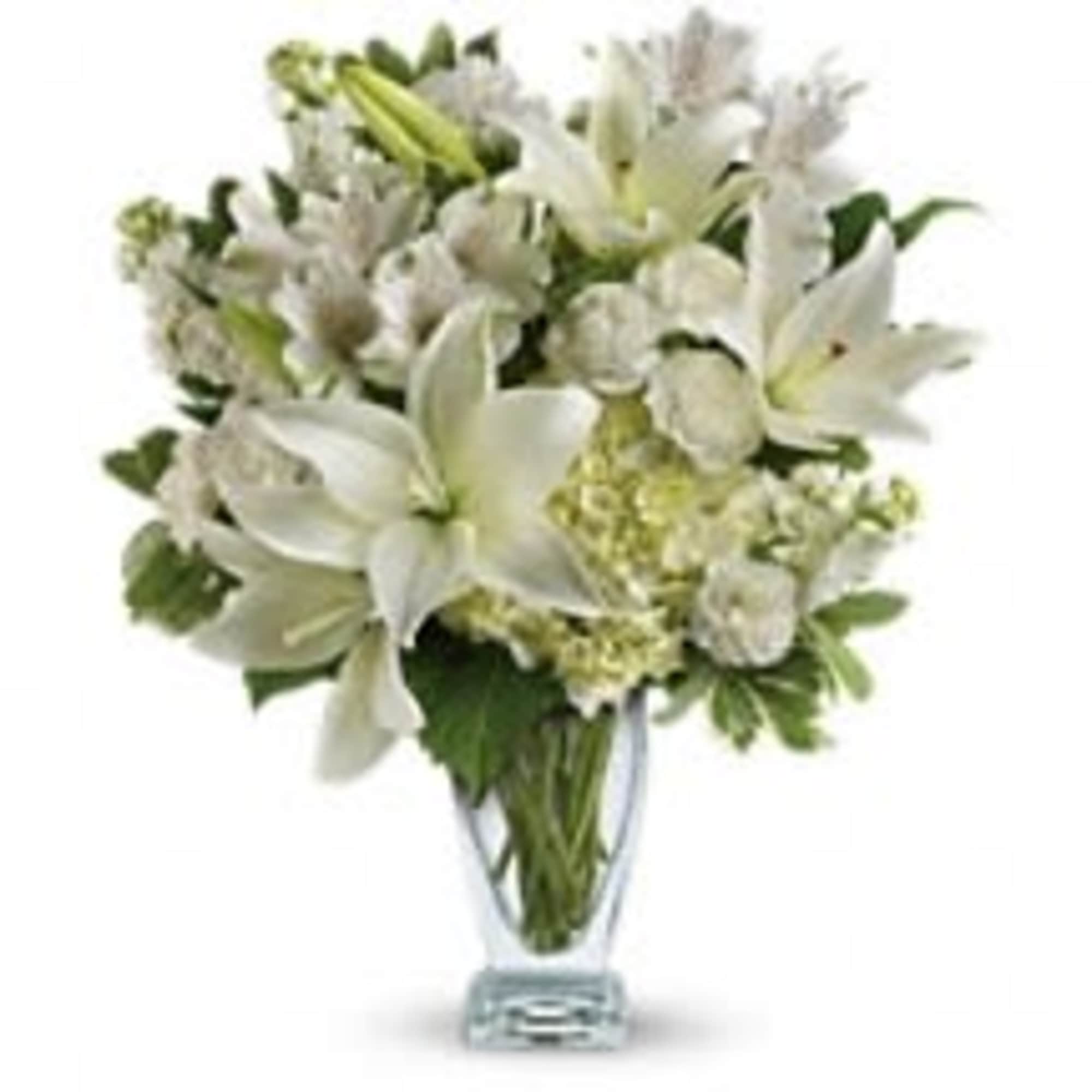 White lilies and pale blooms arranged in a clear glass vase
