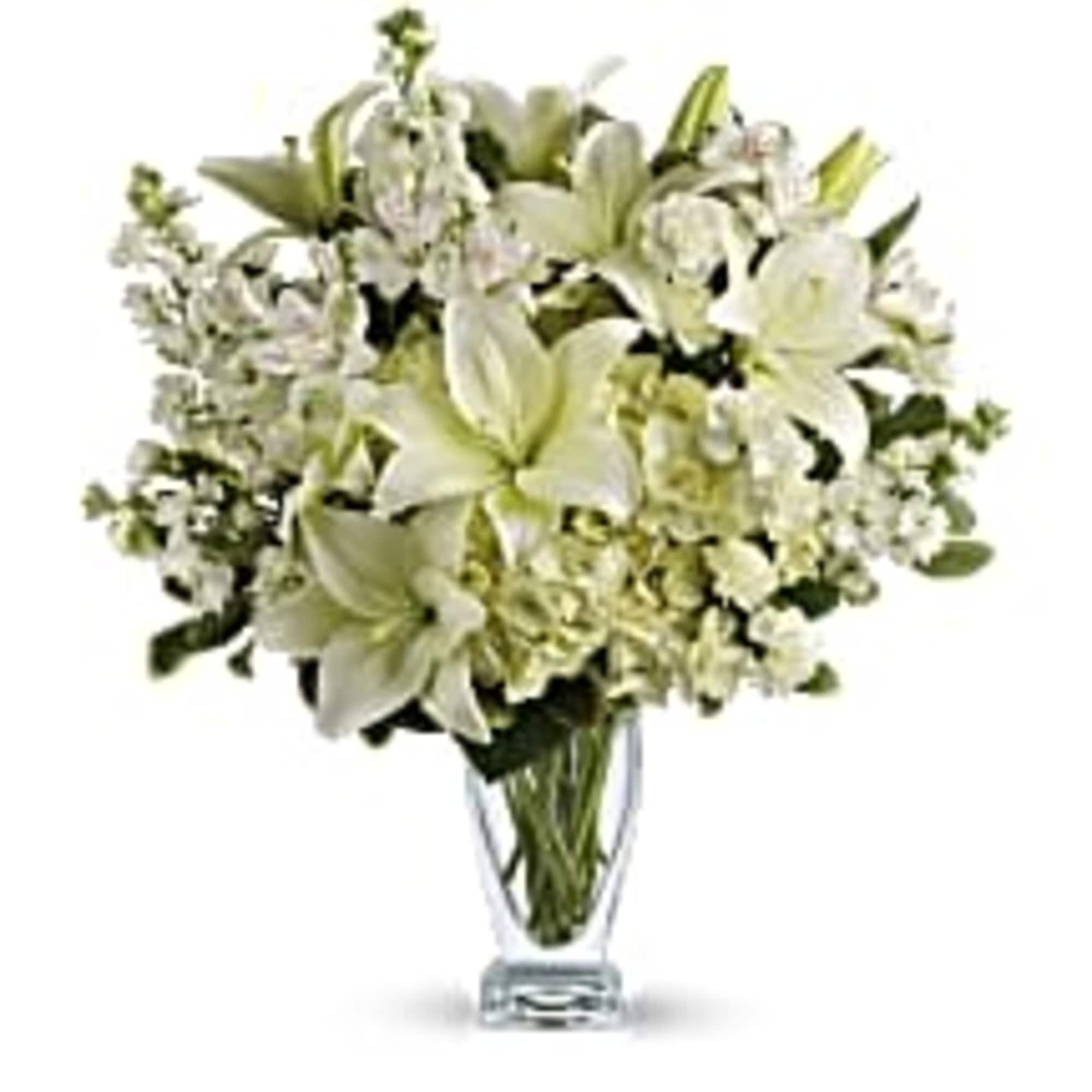 White lilies and small white flowers in a clear glass vase