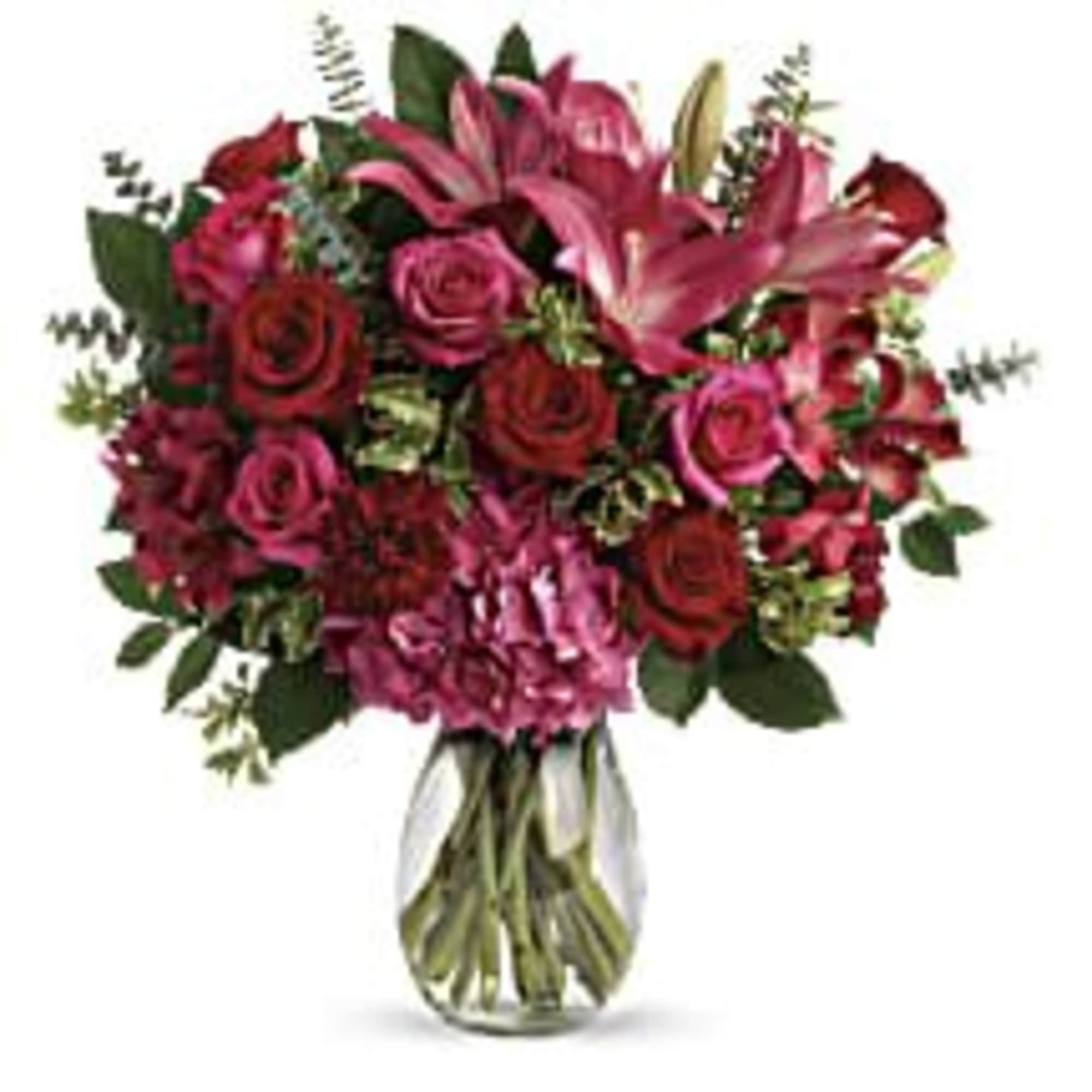 Pink and red rose bouquet with lilies in a glass vase