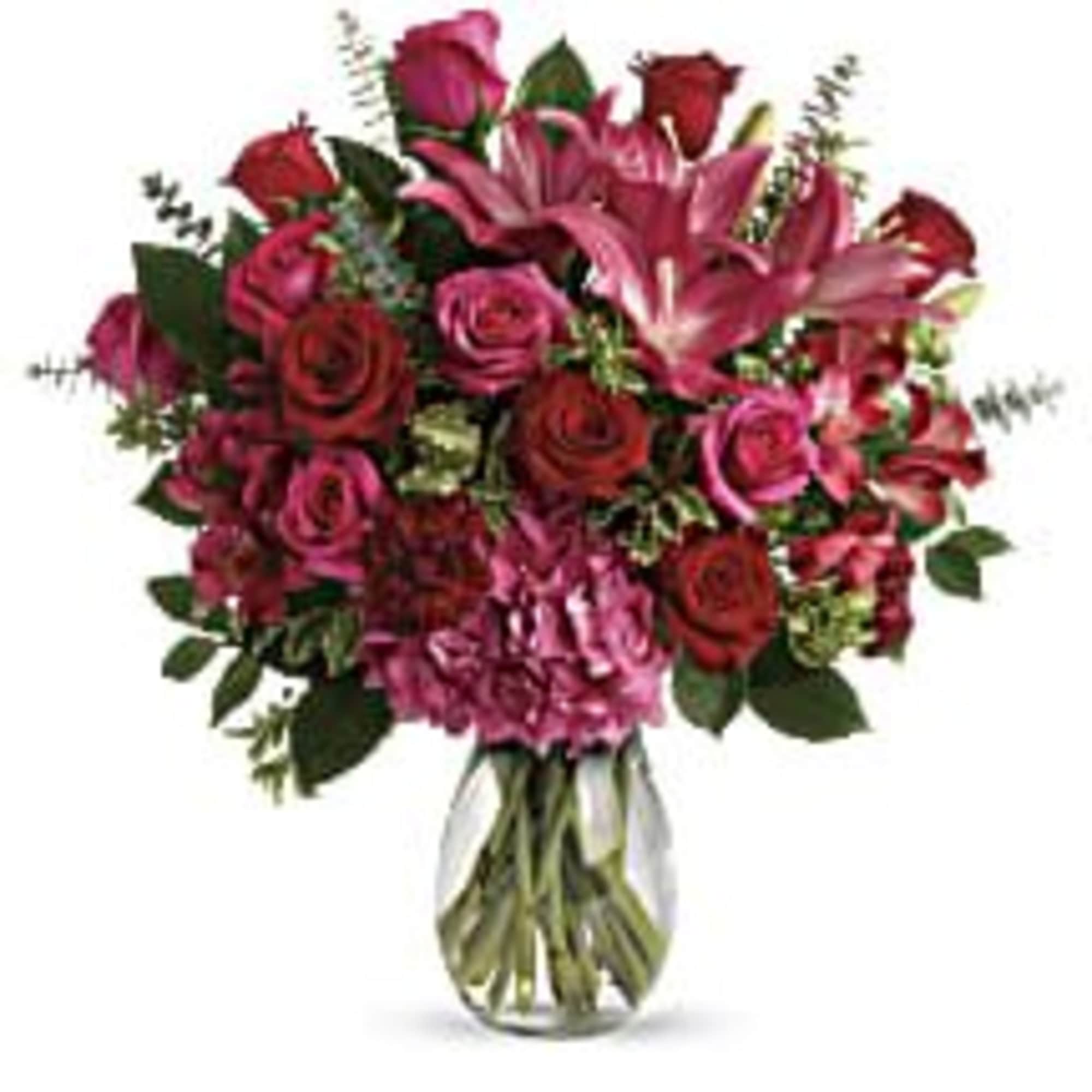 Bouquet of pink lilies and red roses in a clear glass vase