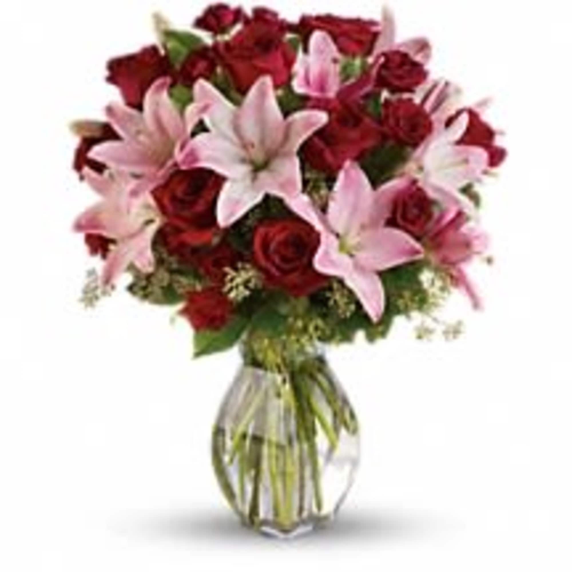 Bouquet of red roses and pink lilies in a clear glass vase
