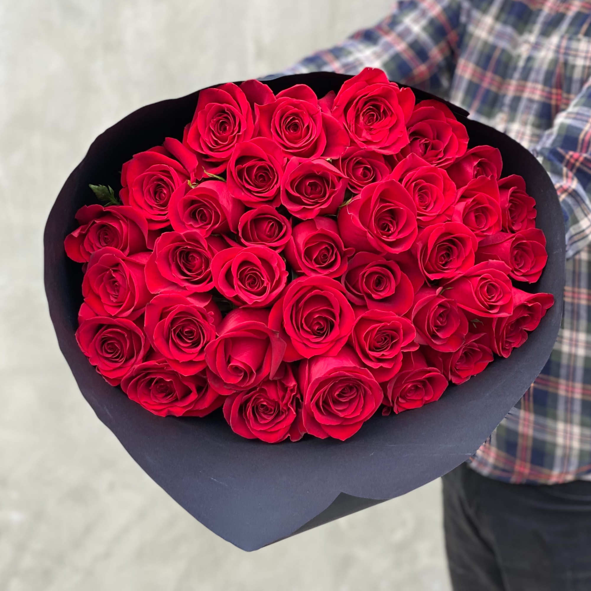 Bouquet of red roses wrapped in dark paper