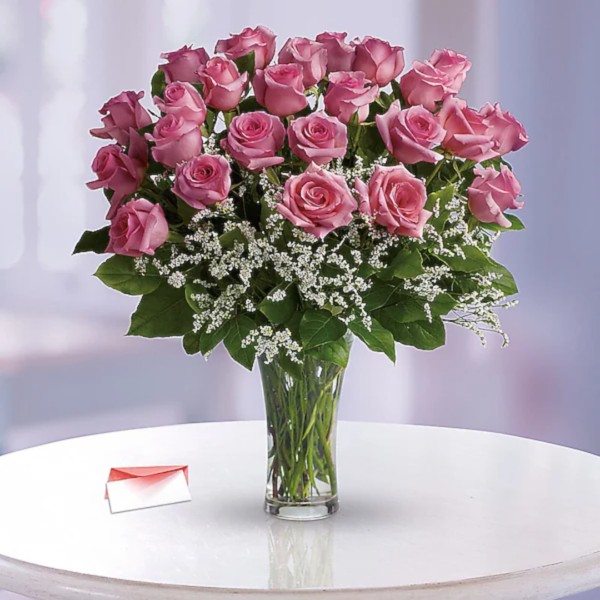Pink roses arranged in a clear glass vase with white filler flowers, photo 2 of 2