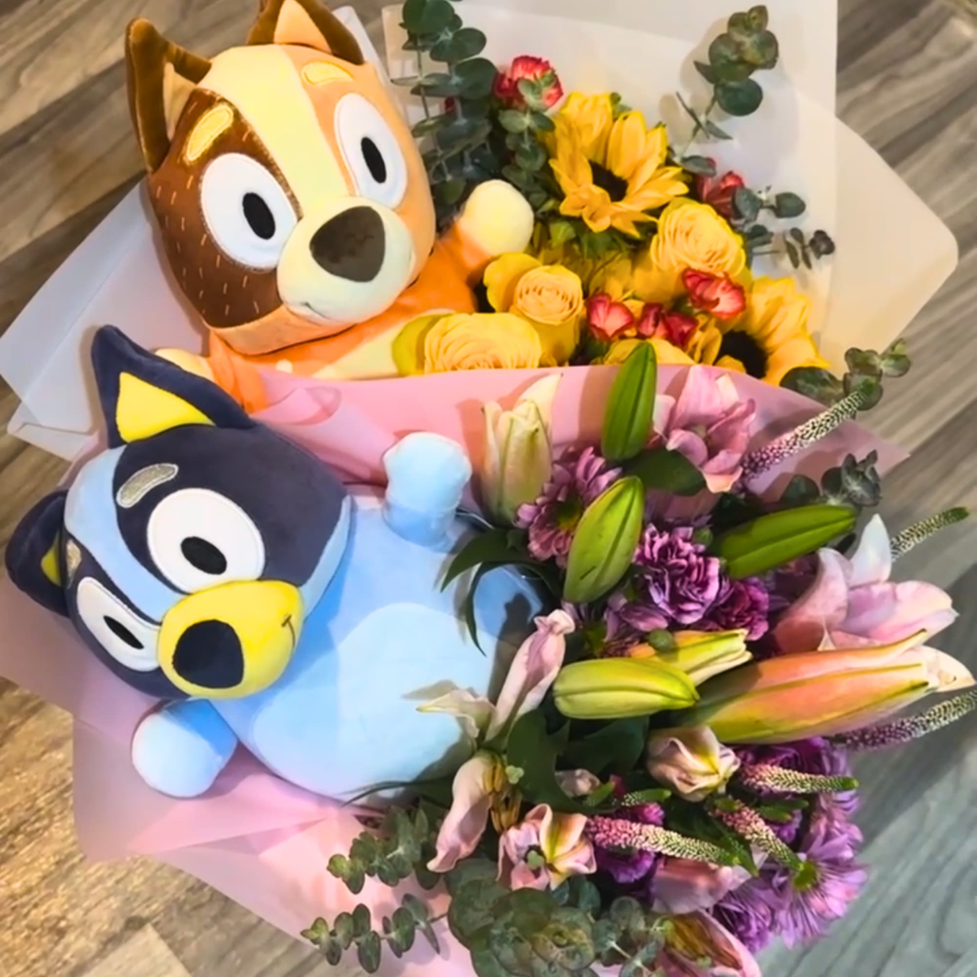 Two plush character bouquets with mixed flowers and pastel wrapping