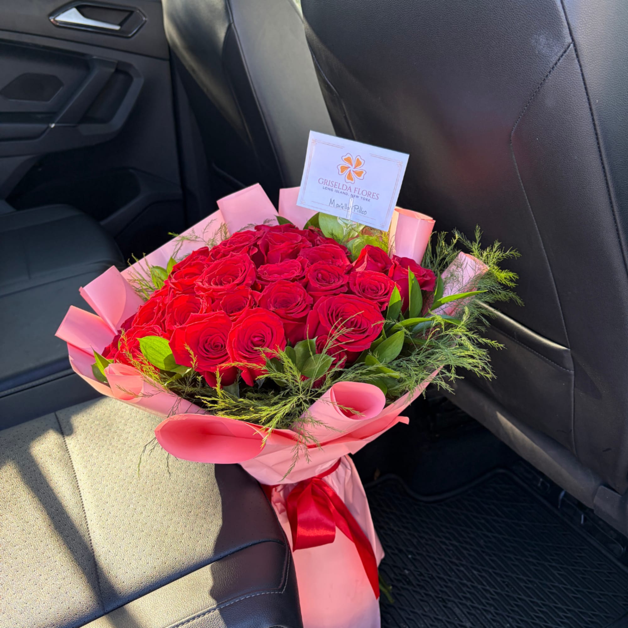 Bouquet of red roses wrapped in pink paper with a red ribbon