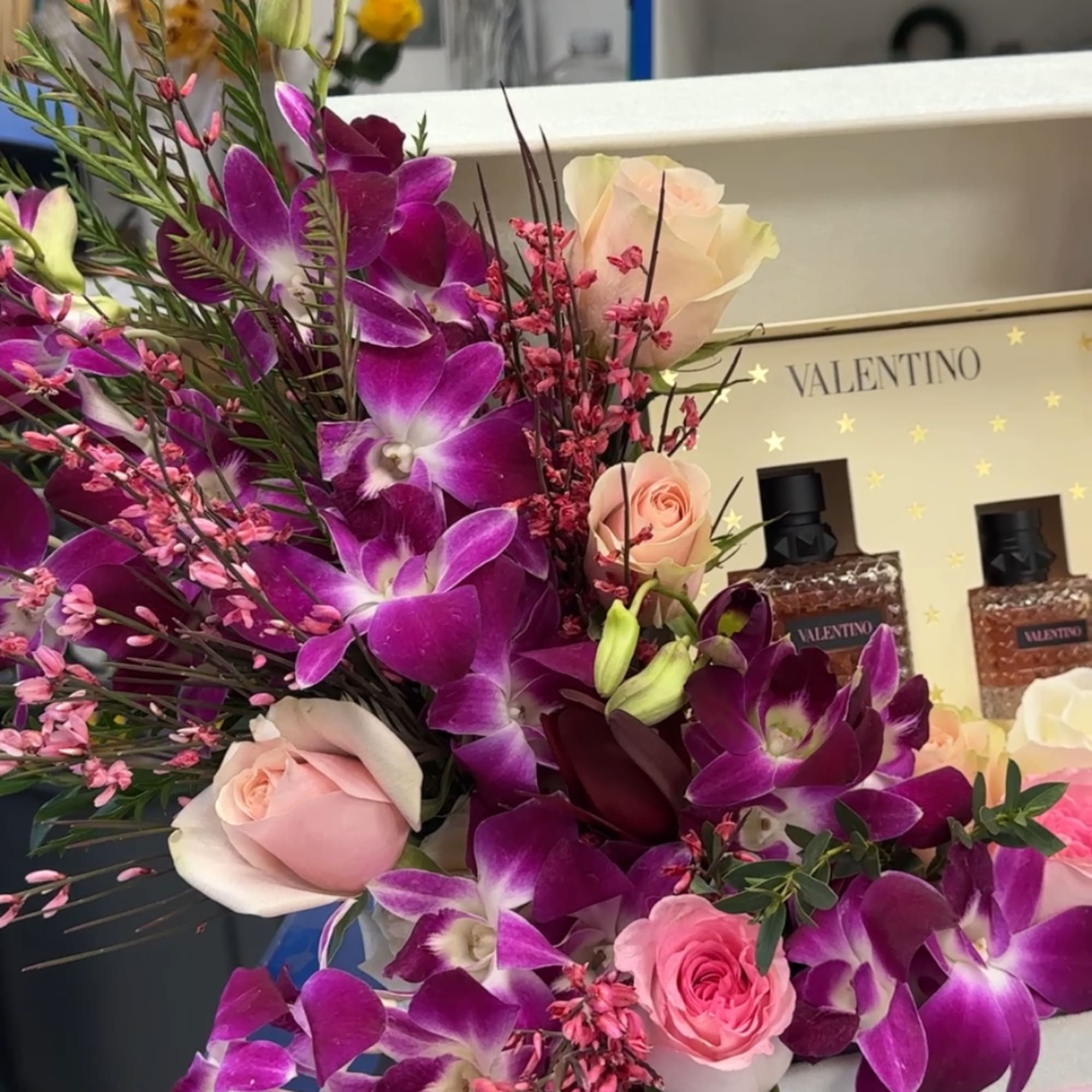 Bouquet of purple orchids and pale pink roses in a gift box
