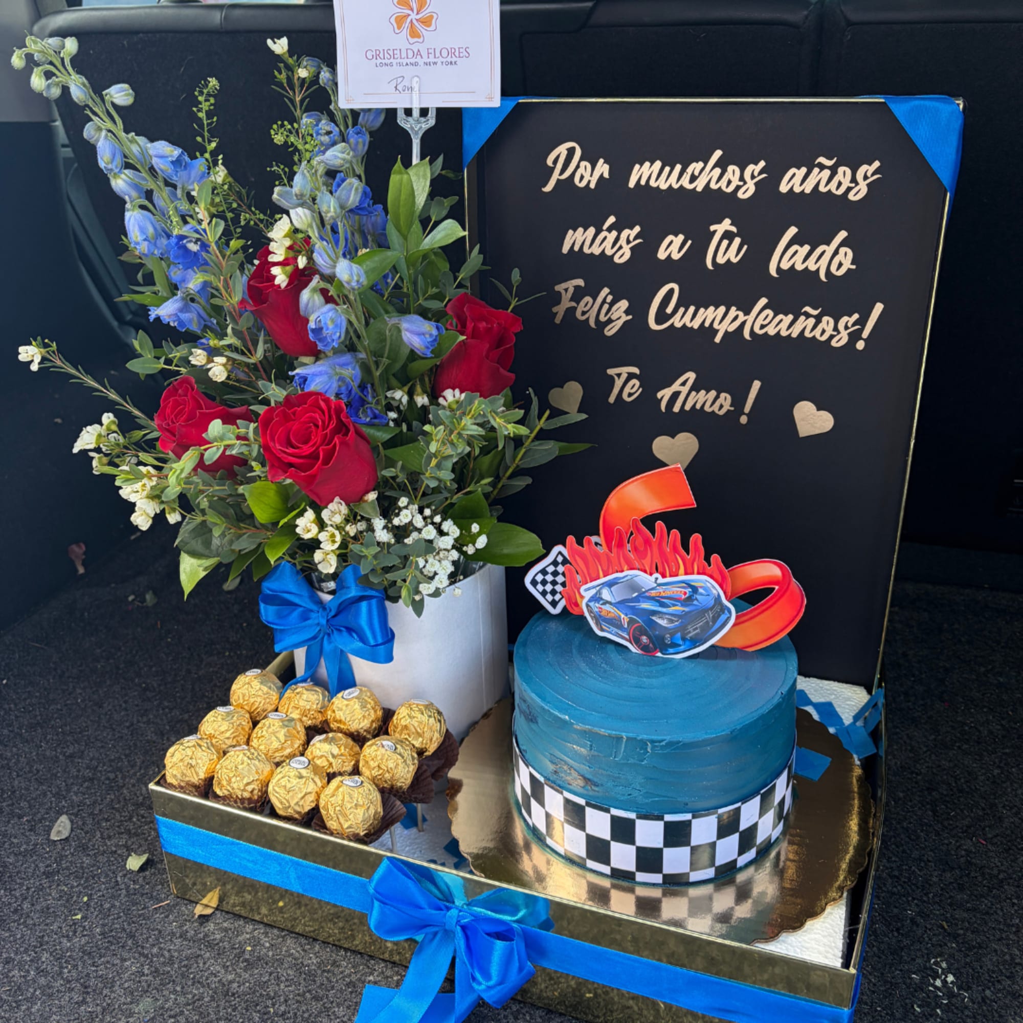 Gift box with red roses, blue flowers, chocolates, and a blue cake