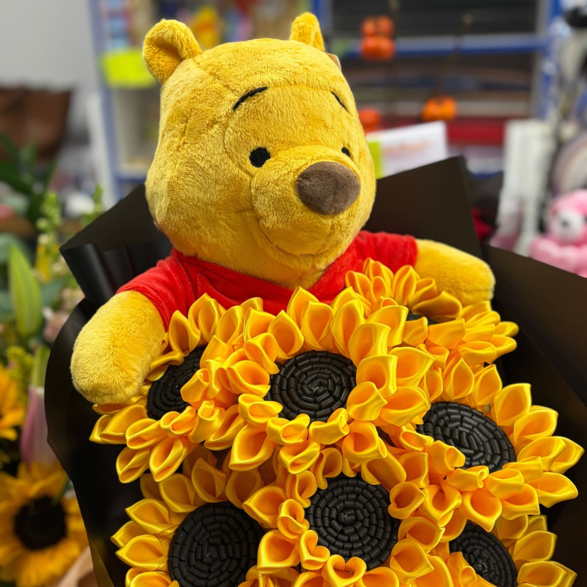 Winnie the Pooh plush holding a bouquet of yellow sunflower-like flowers