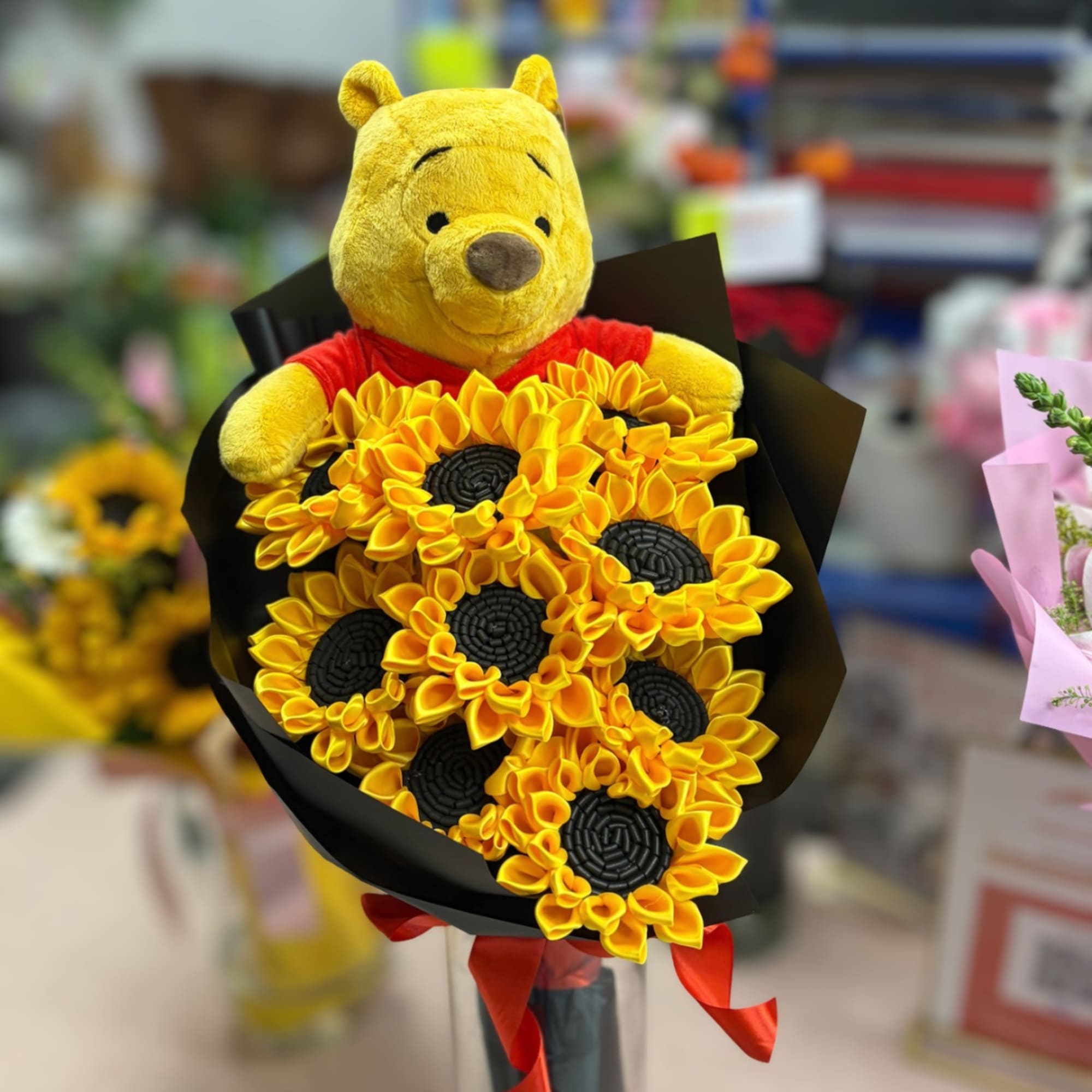 Winnie the Pooh plush holding a bouquet of yellow sunflowers