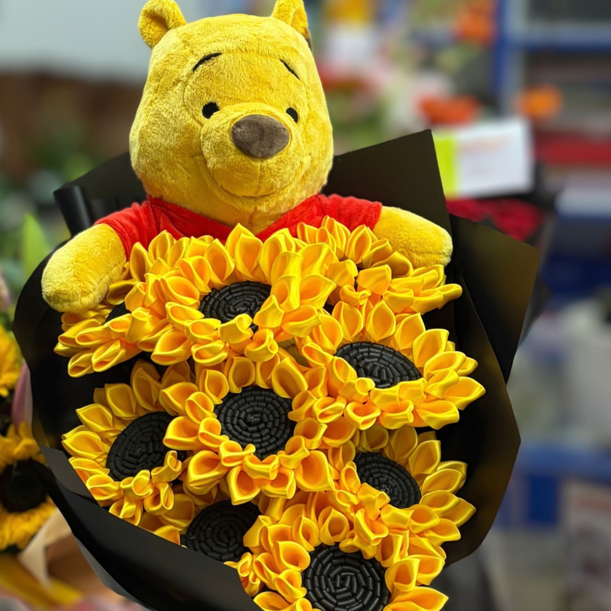 Winnie the Pooh plush holding a sunflower bouquet
