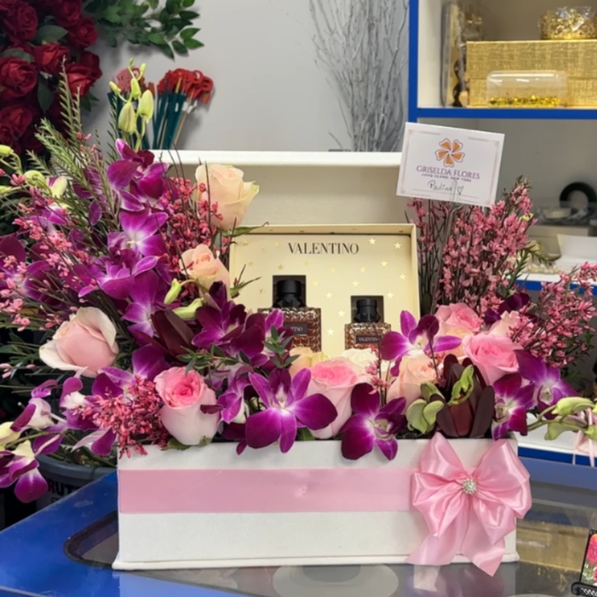 Pink and purple floral gift box with roses and orchids, plus perfume bottles
