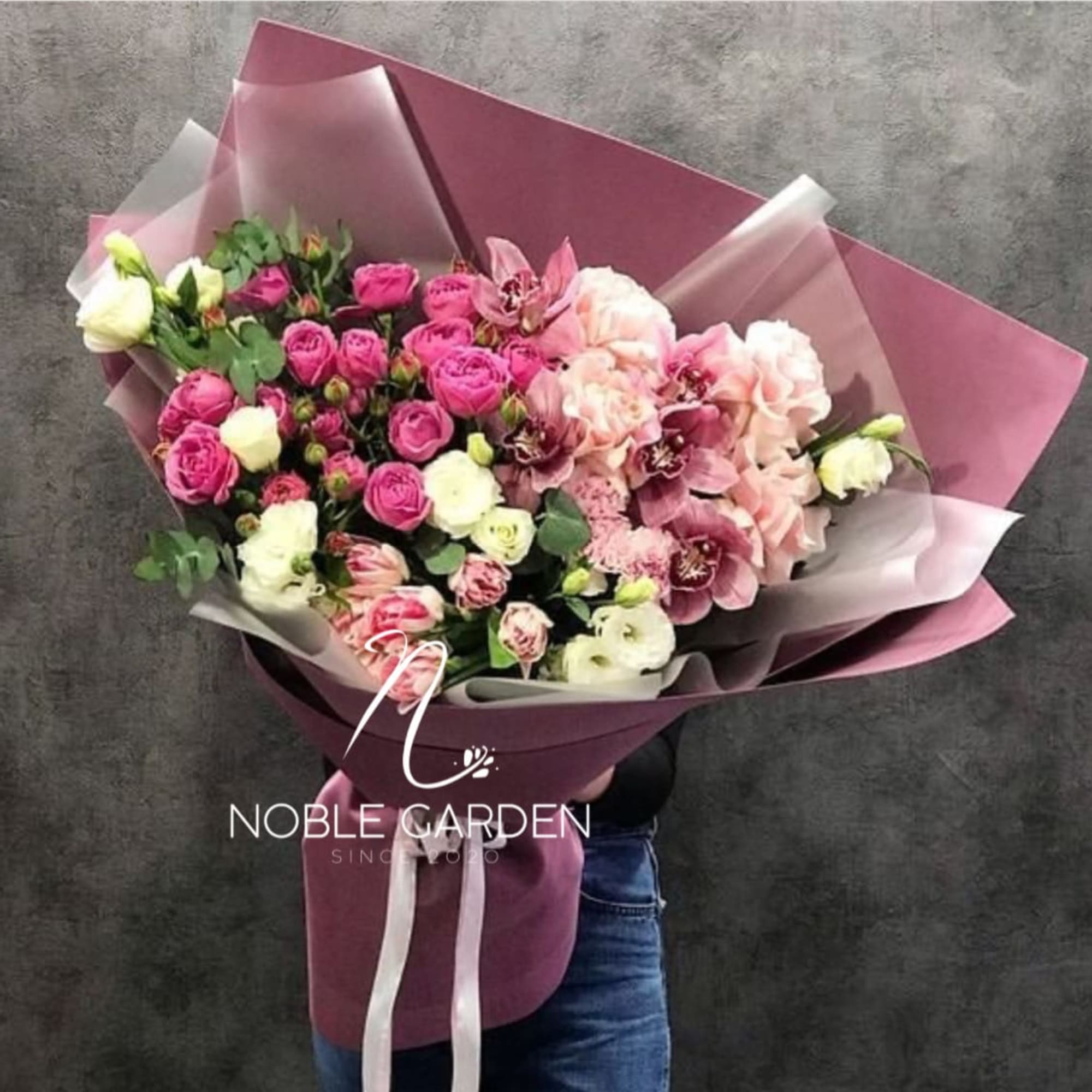 Bouquet of pink and white roses with pale pink orchids wrapped in mauve paper