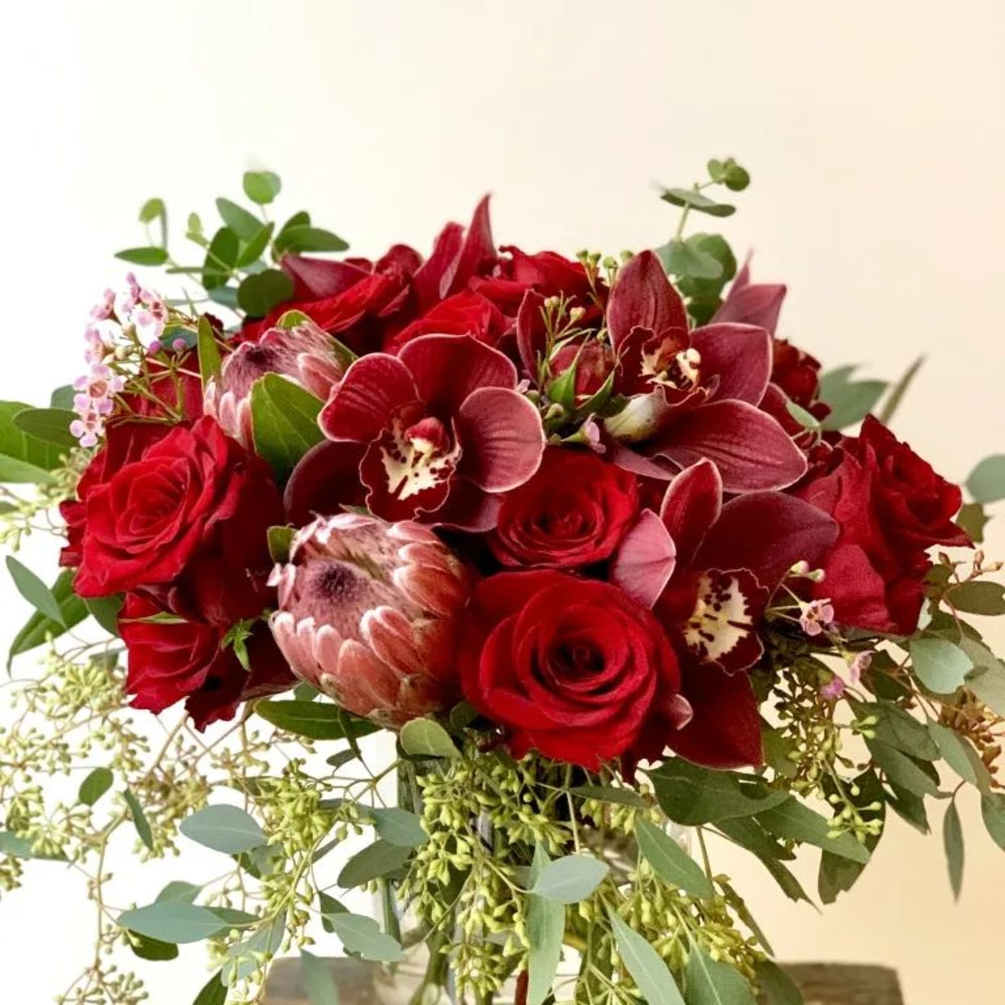 Red roses and burgundy orchids in a glass vase