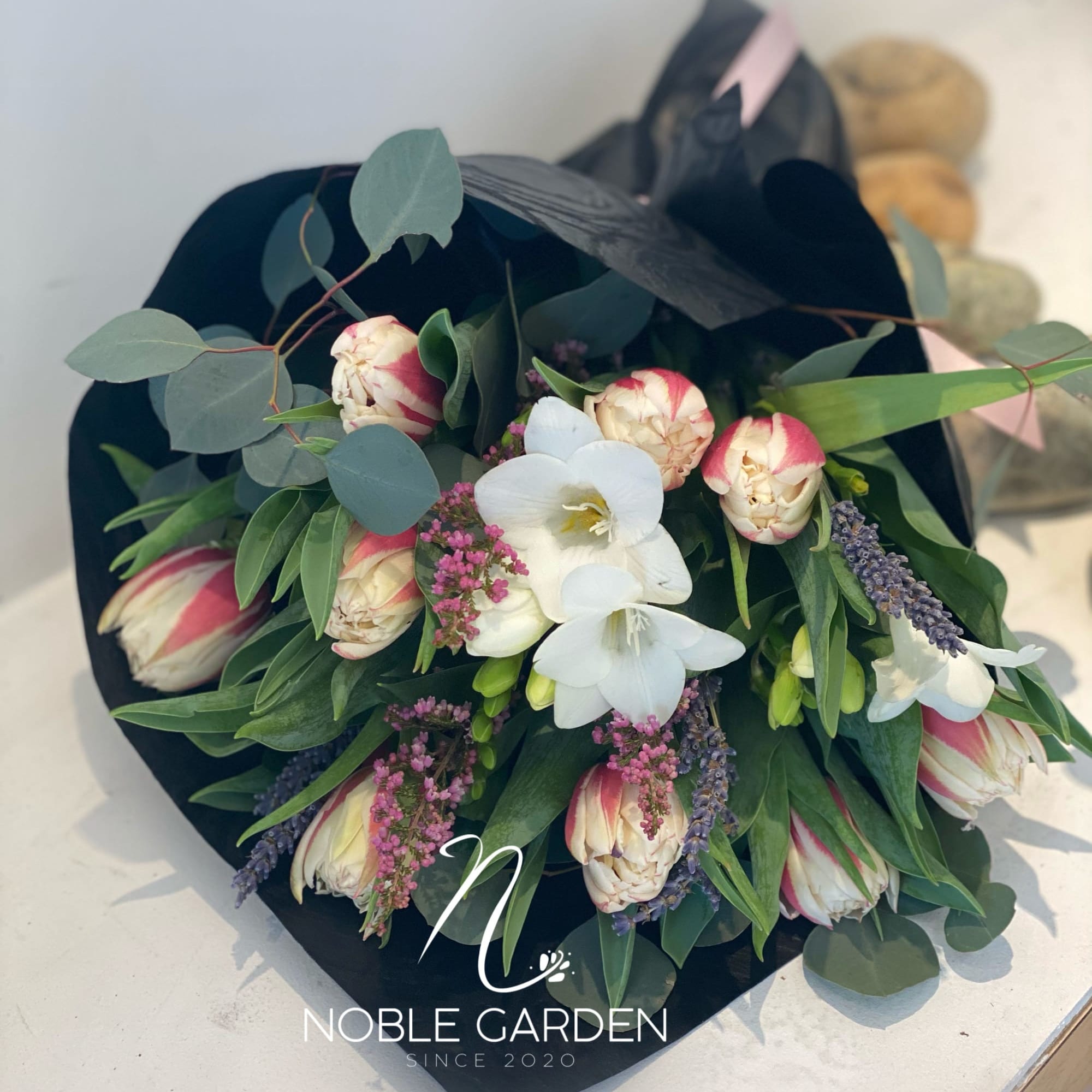 Bouquet of white and pink flowers wrapped in black paper