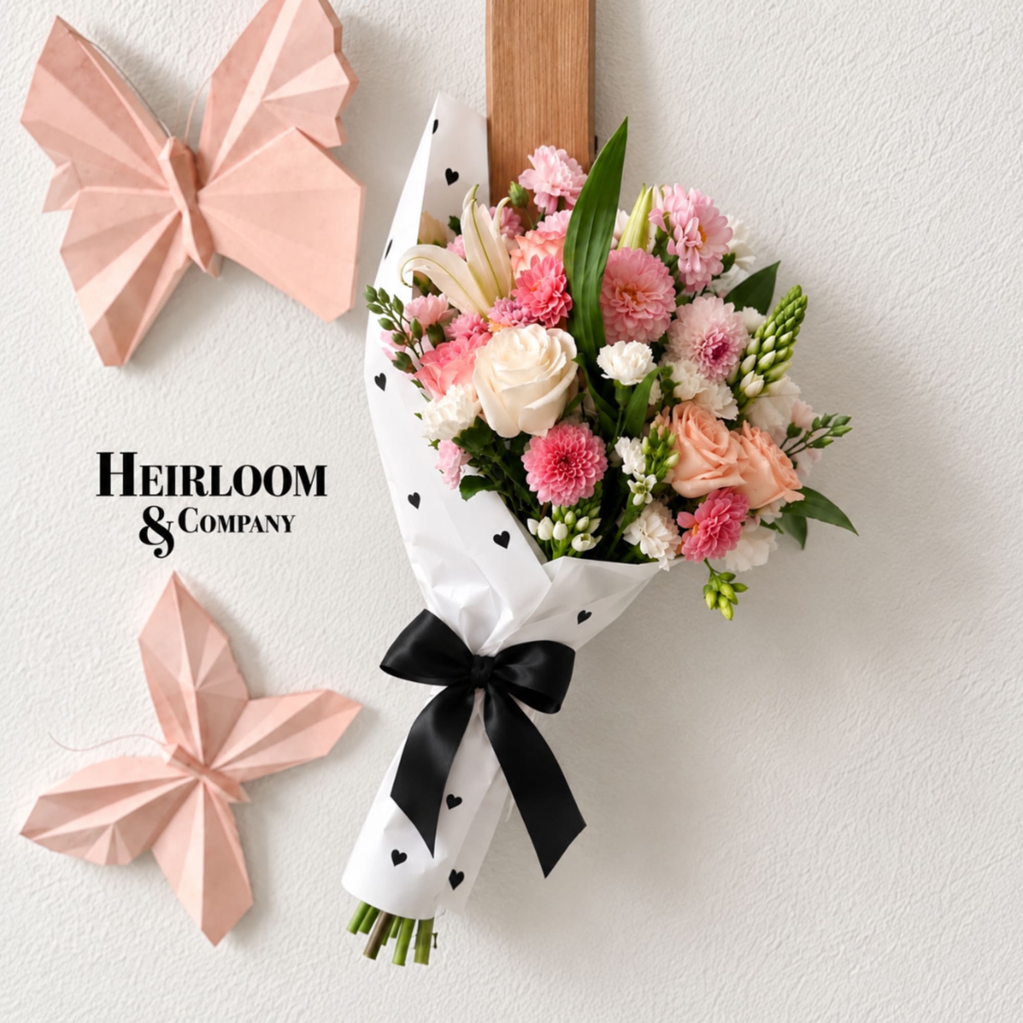 Pink and white bouquet wrapped in paper with a black ribbon