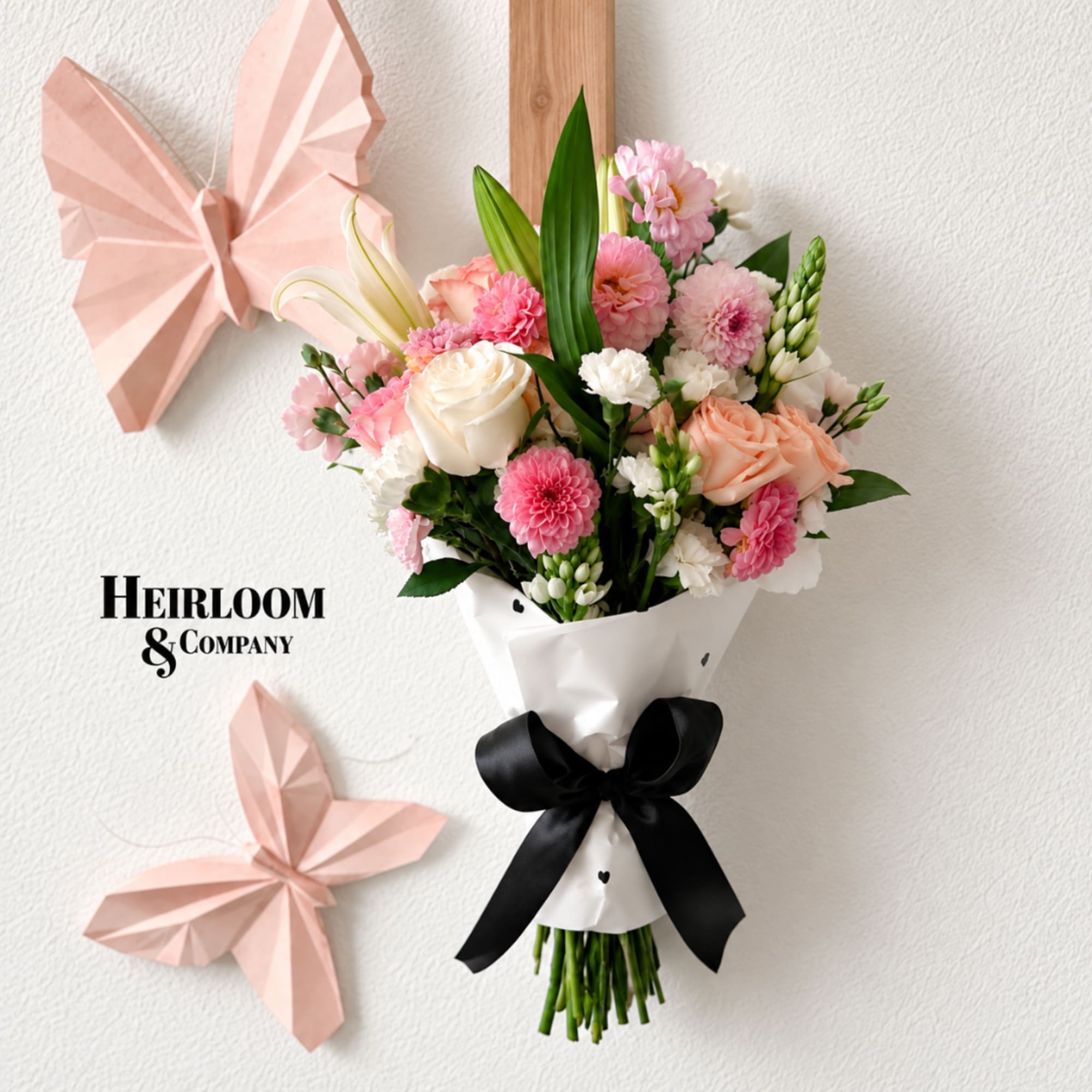 Pink and white flower bouquet wrapped in white paper with a black ribbon
