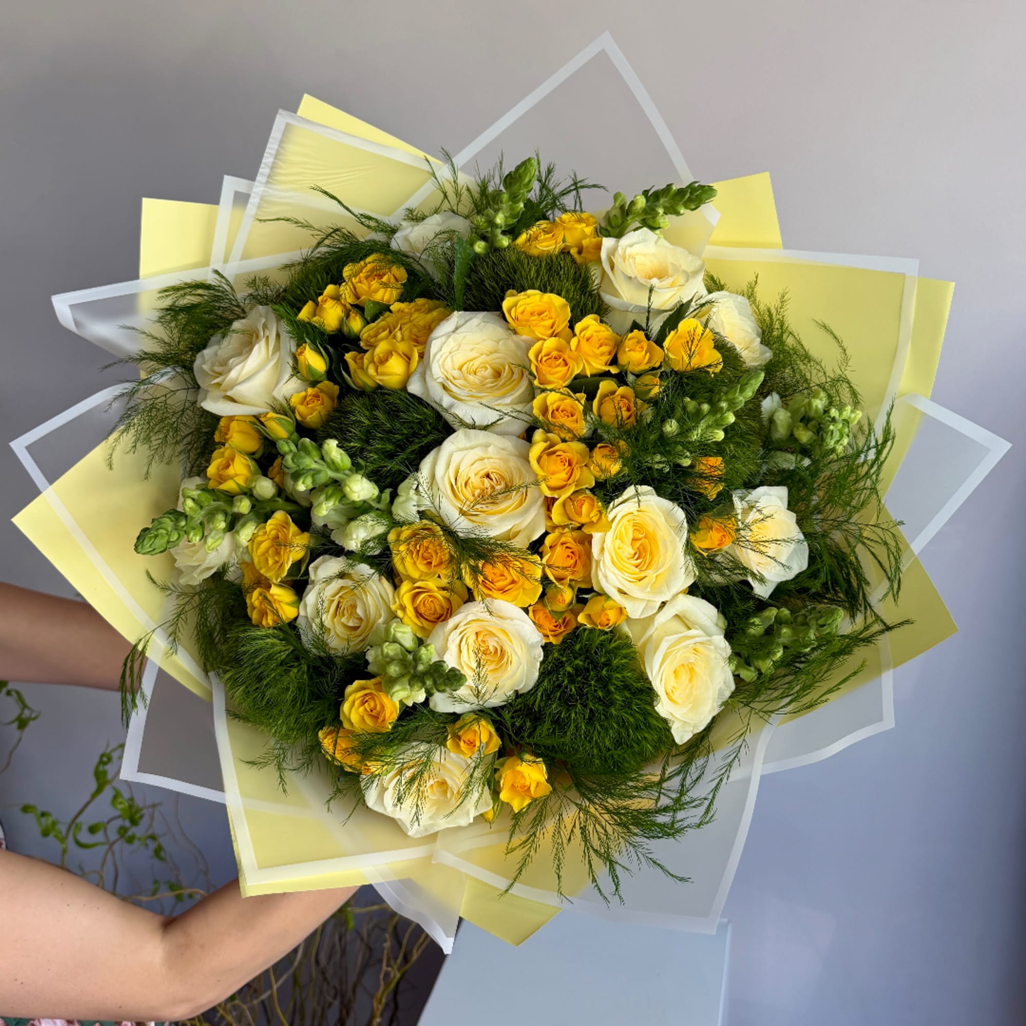 Bouquet of white and yellow roses wrapped in translucent paper
