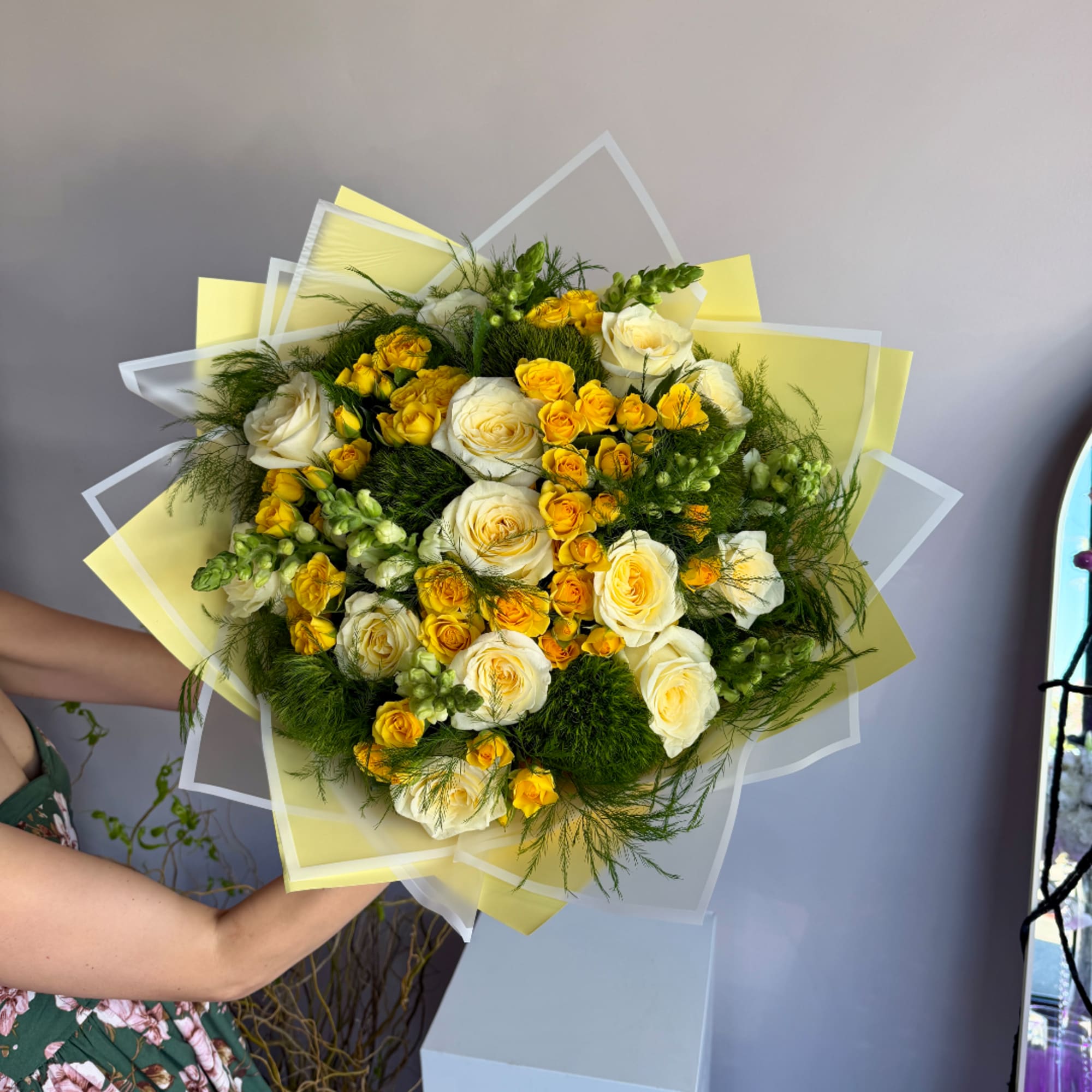 Bouquet of white and yellow roses wrapped in translucent paper