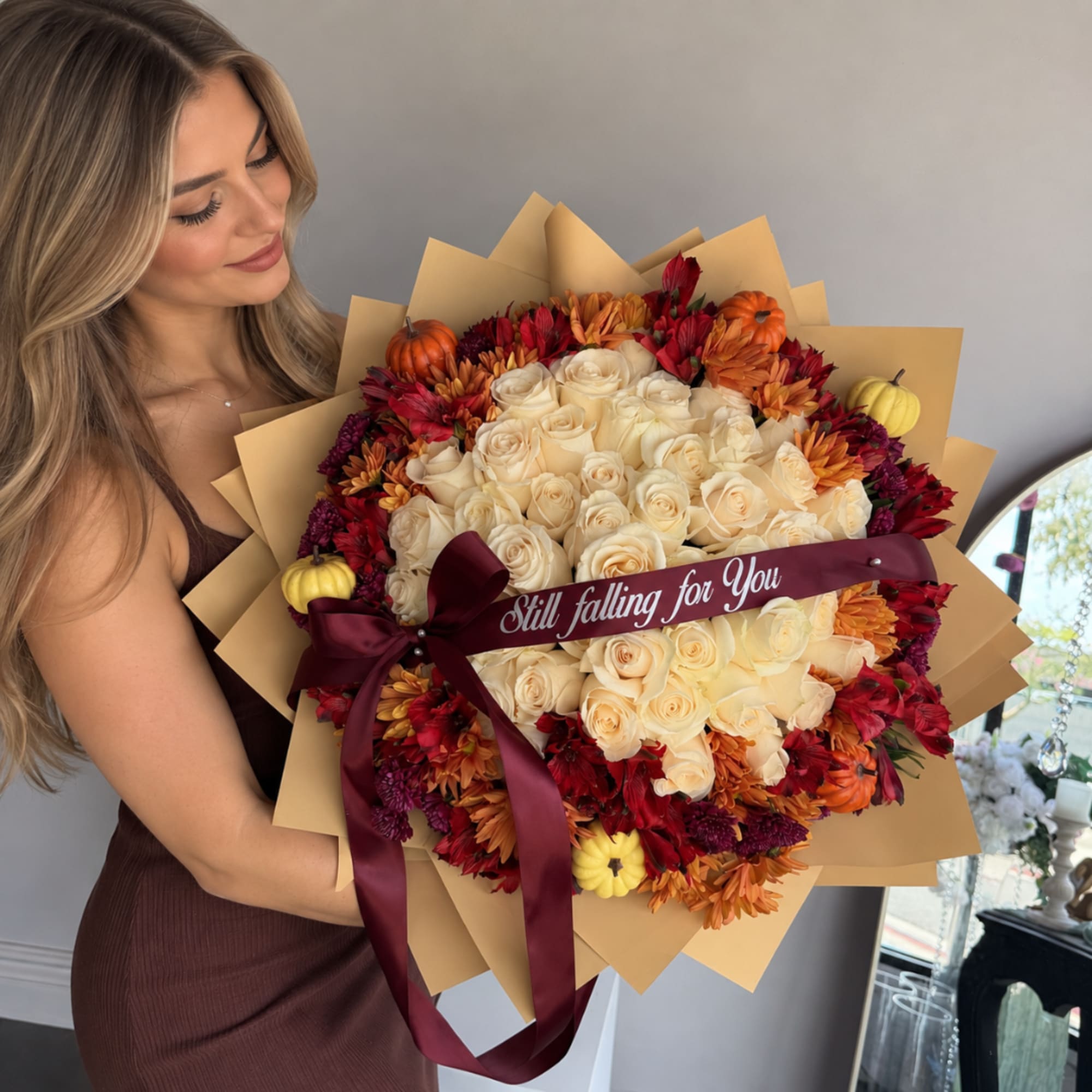 Woman holding a bouquet of cream roses and autumn flowers with a ribbon