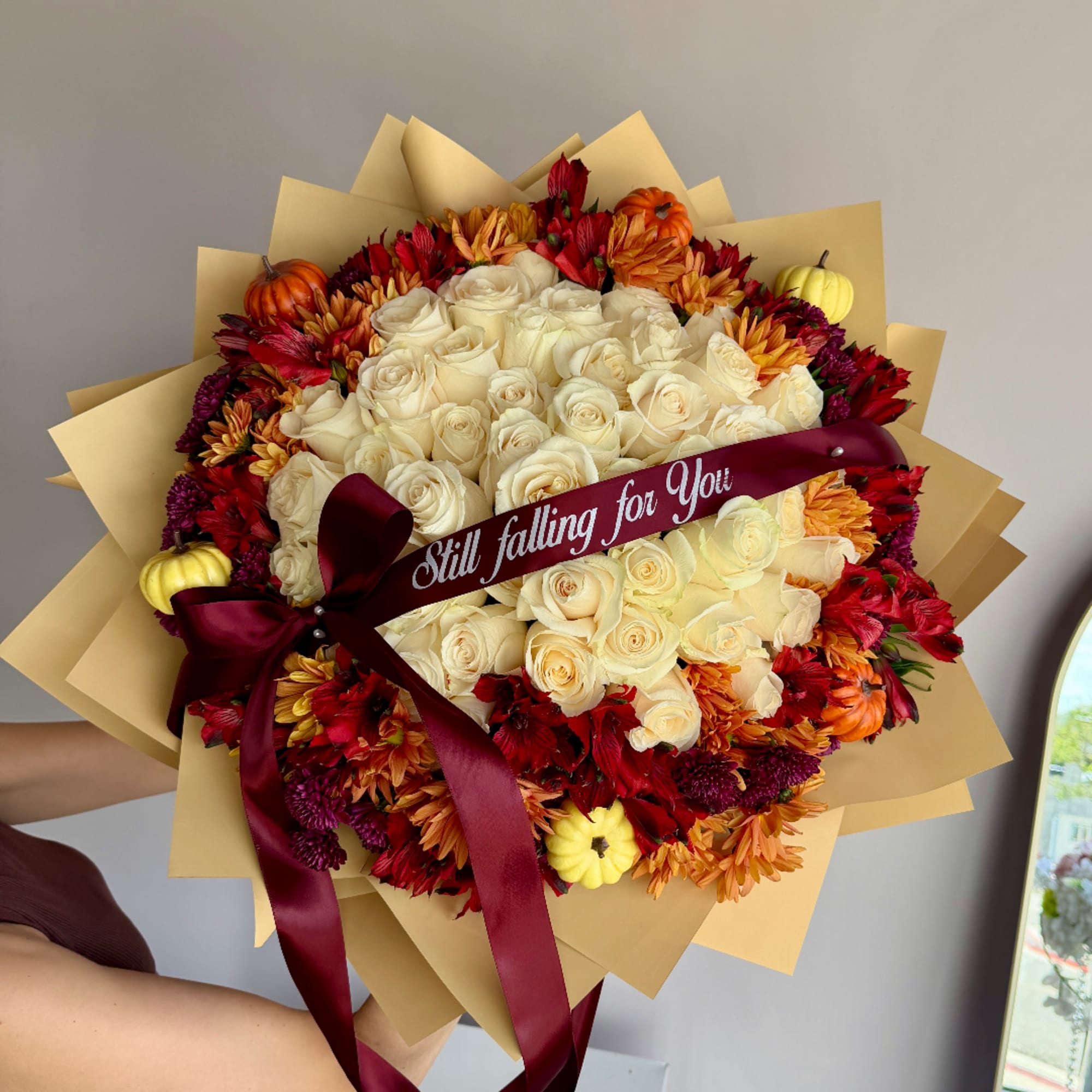 Bouquet of cream roses and autumn flowers wrapped with a burgundy ribbon