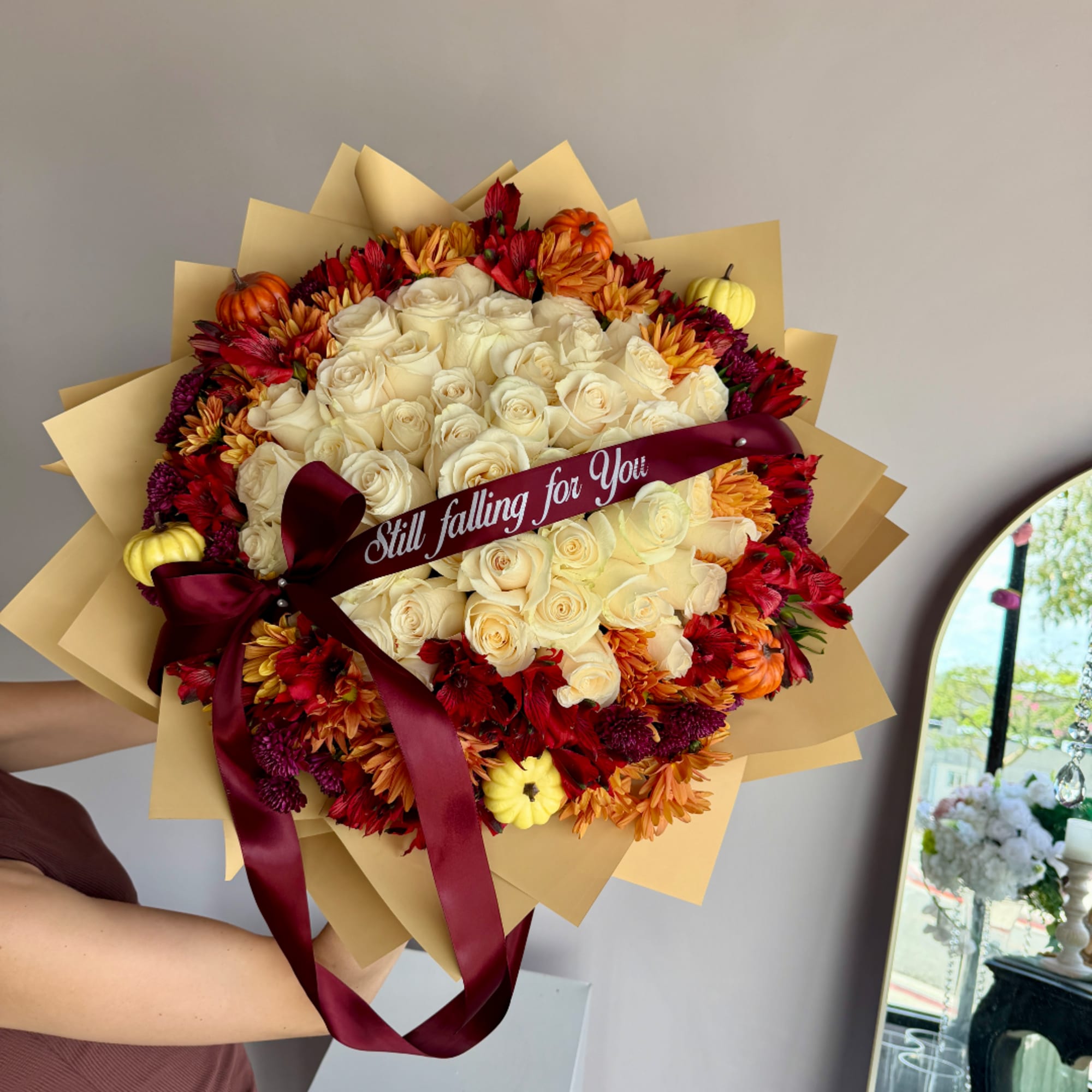 Bouquet of cream roses with red and orange flowers, wrapped with a burgundy ribbon