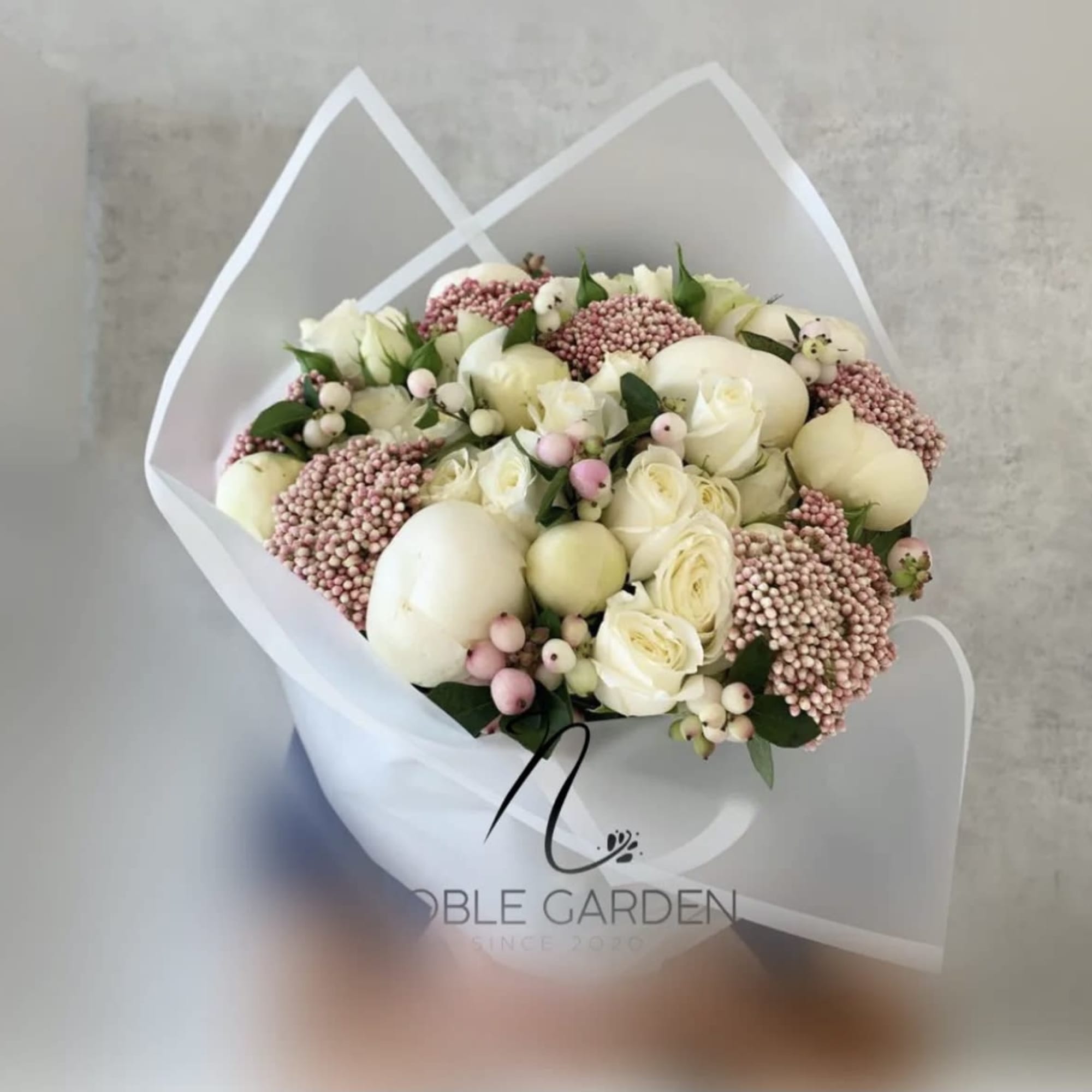 Bouquet of white roses and pink berries wrapped in white paper