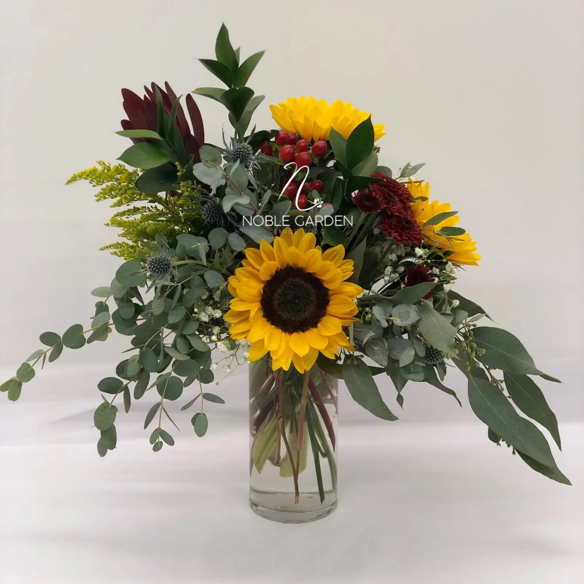 Sunflowers and mixed greenery in a clear glass vase
