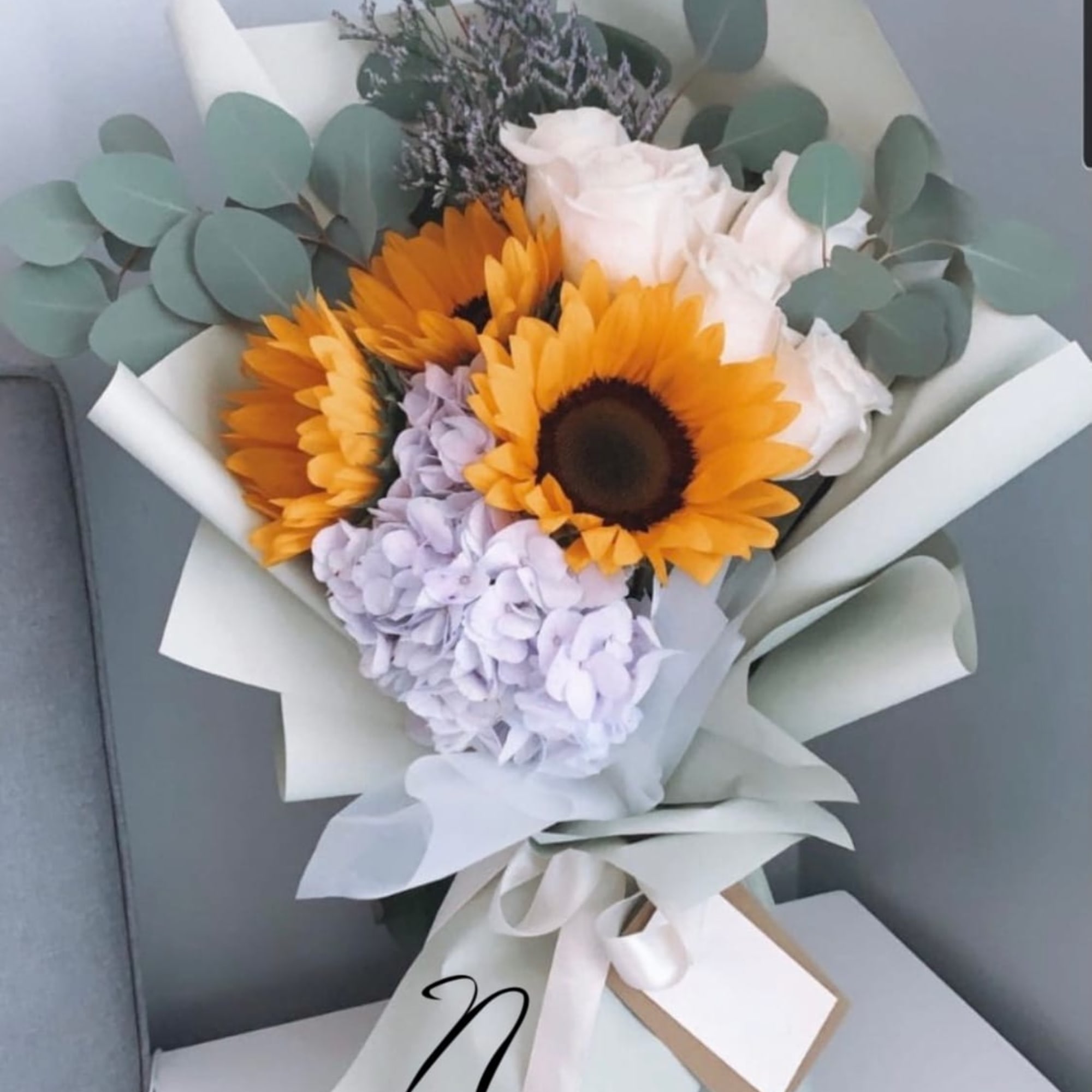Bouquet of sunflowers, white roses, and lavender hydrangea with eucalyptus wrap