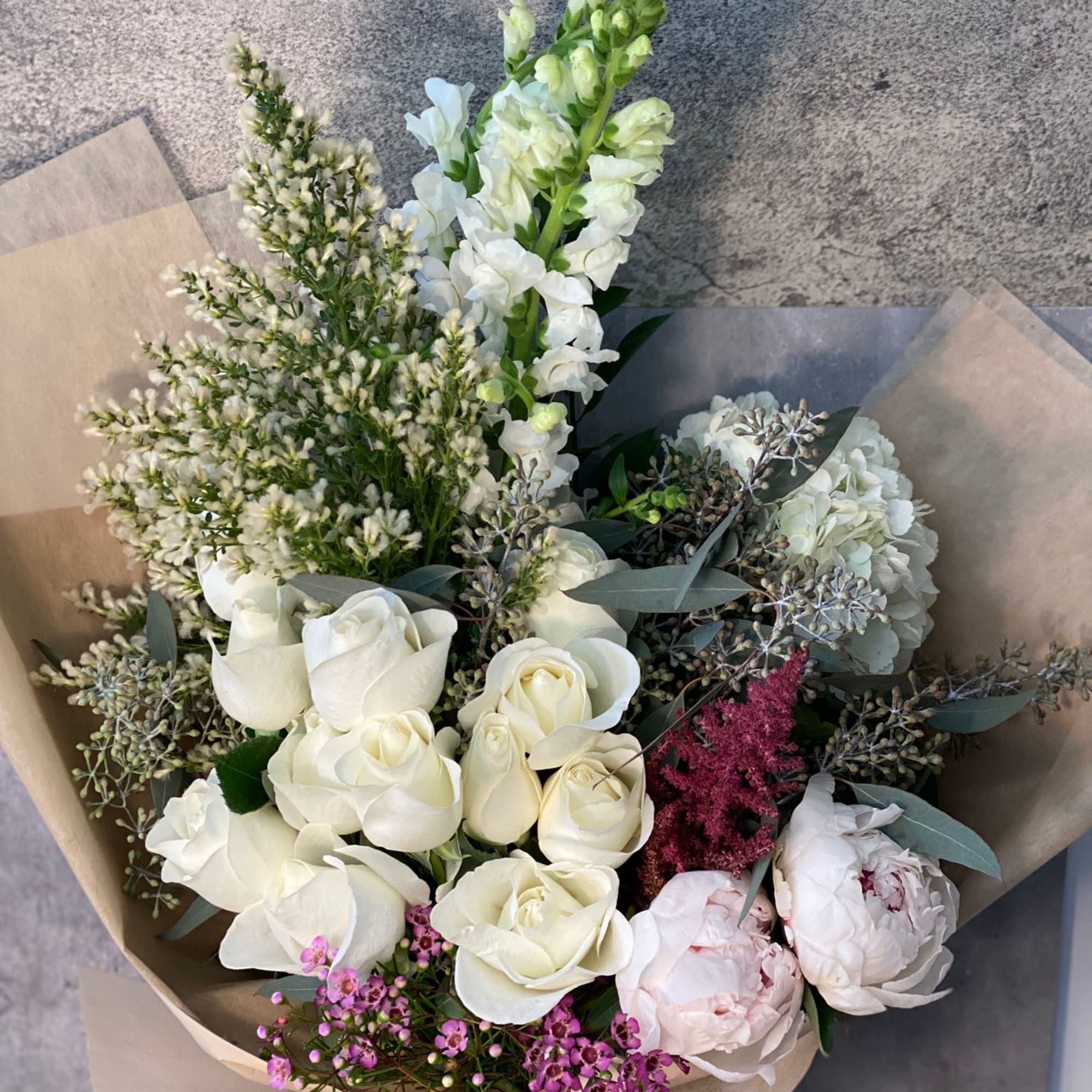 Bouquet of white roses, peonies, and snapdragons with pink accents