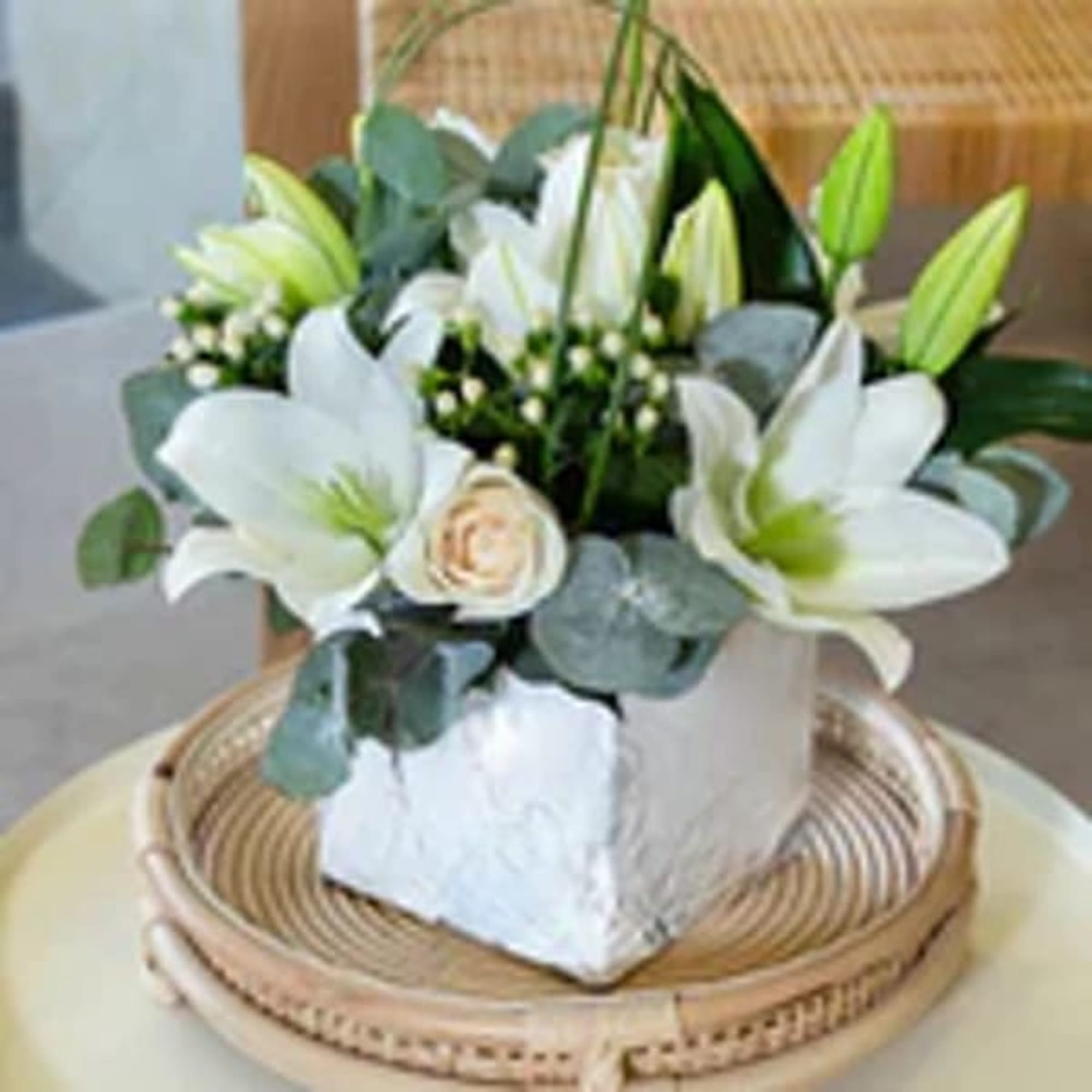 White lilies and a cream rose in a square white vase