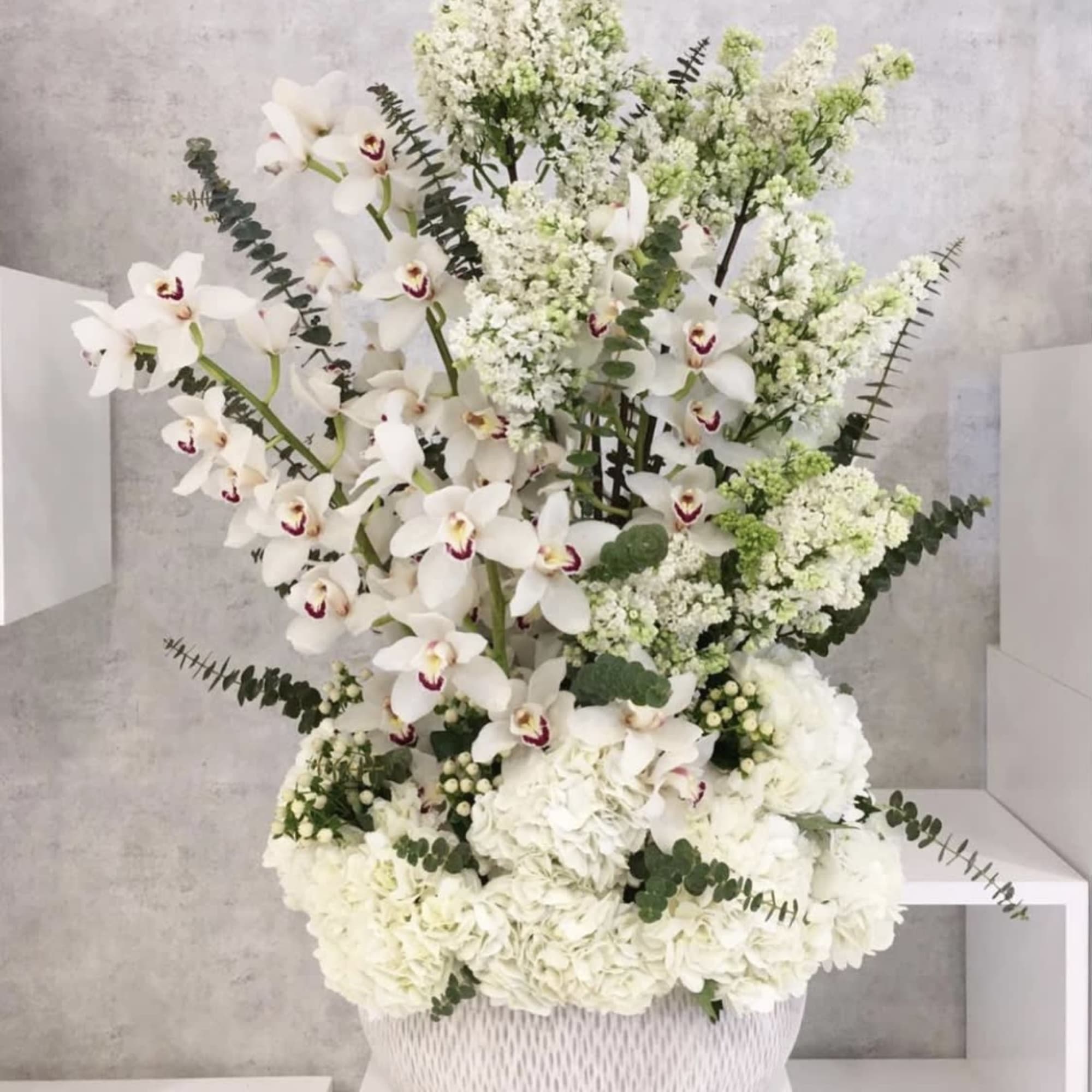 White orchids and hydrangeas arranged in a white basket