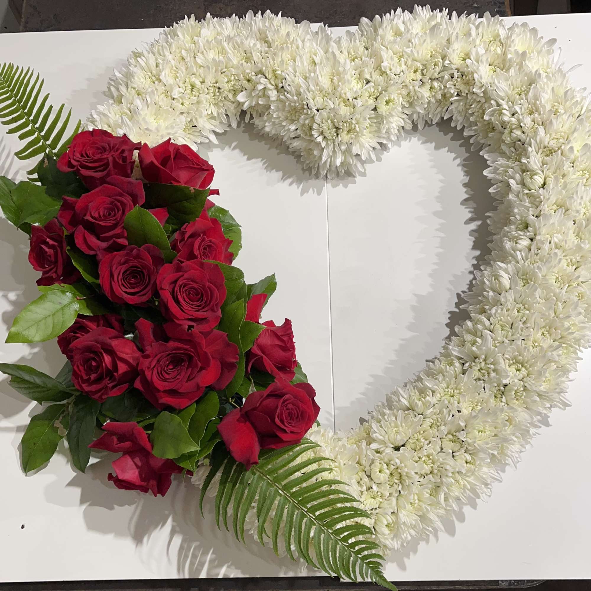 Heart-shaped floral arrangement with red roses and white chrysanthemums
