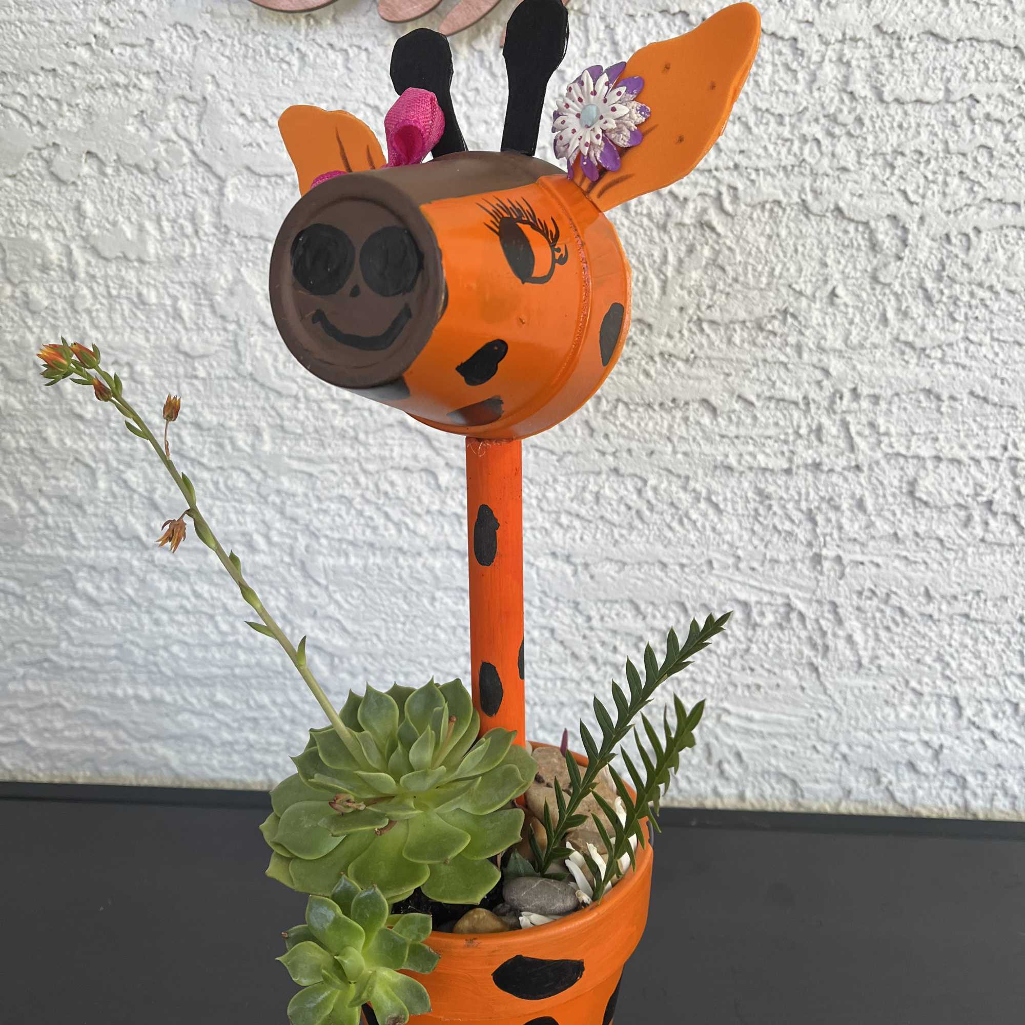 Painted giraffe planter with succulents and small decorative flowers