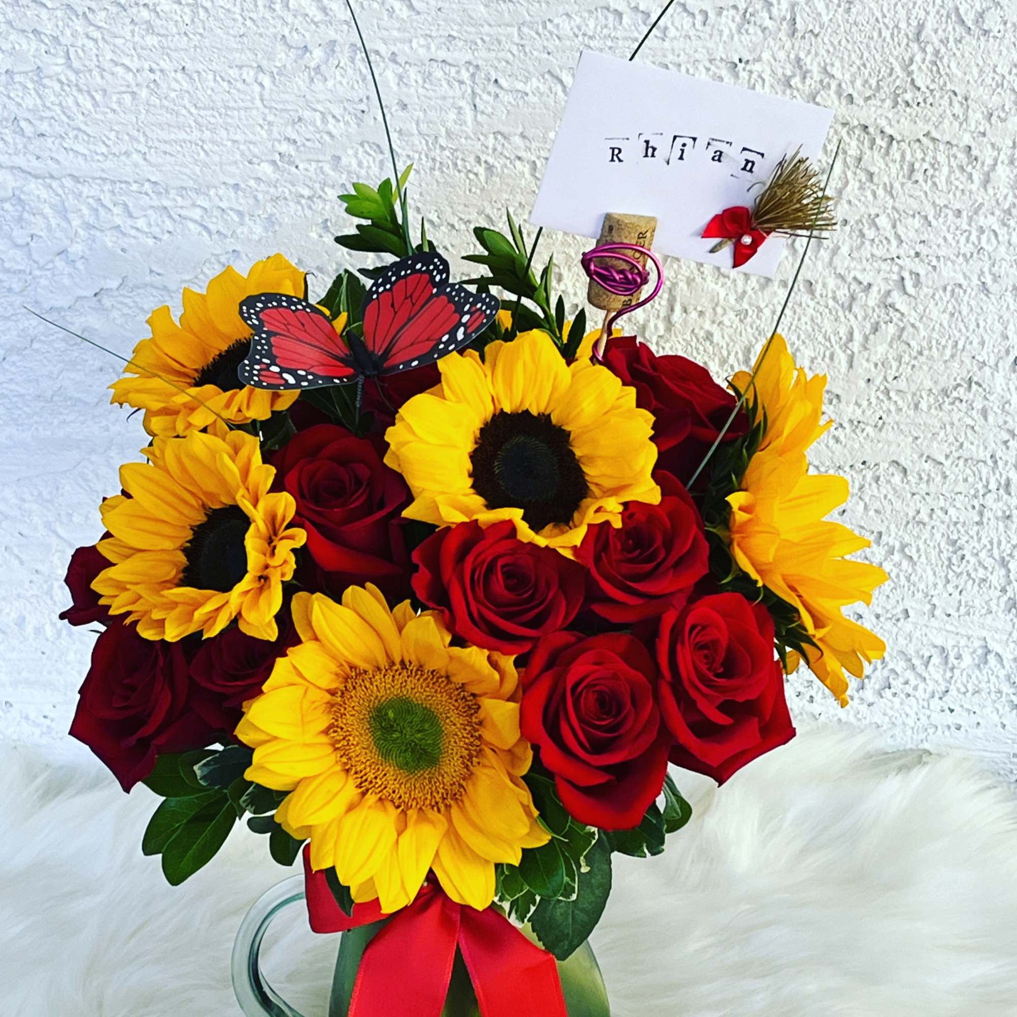 Bouquet of red roses and yellow sunflowers in a glass mug with a red ribbon