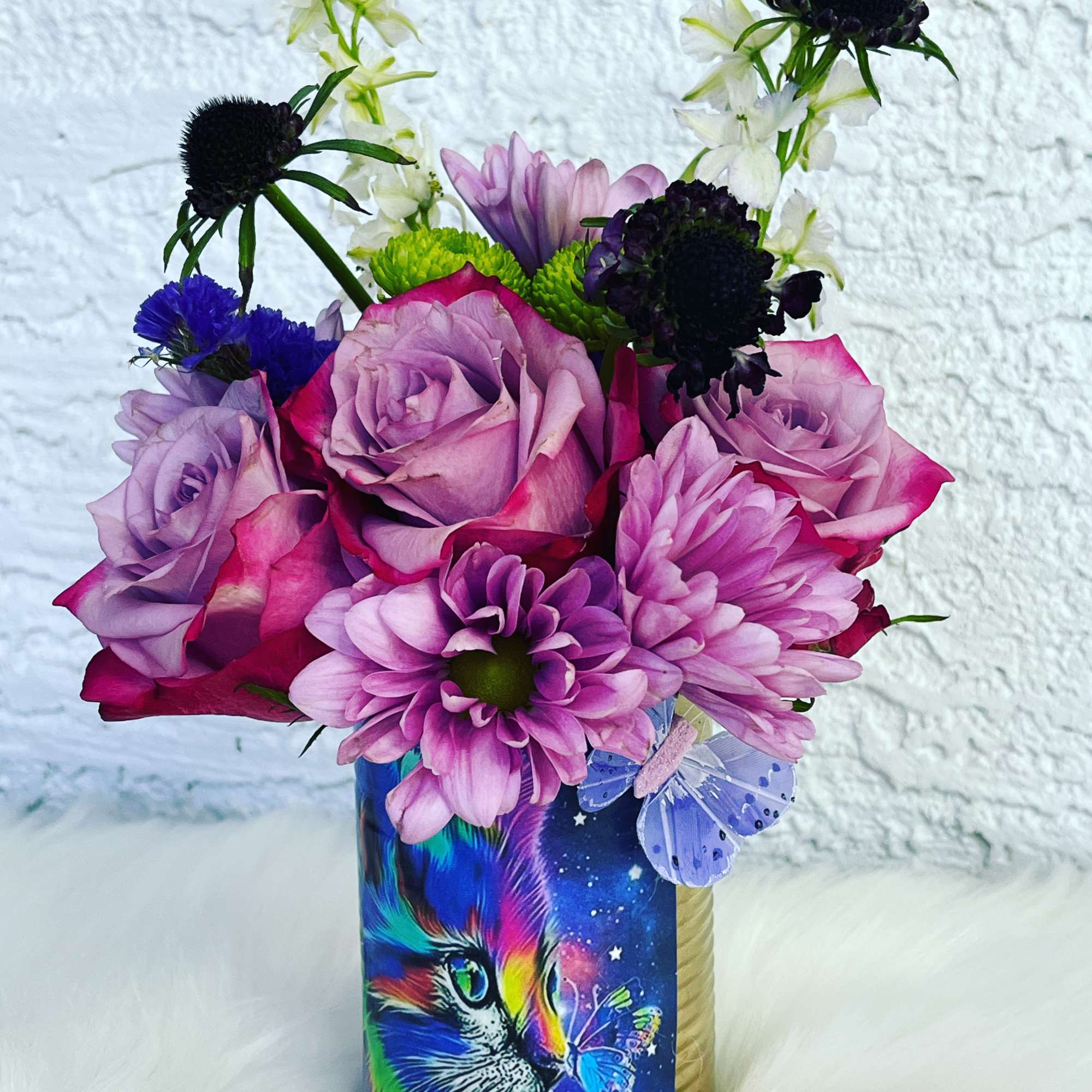 Pink and purple flower bouquet in a decorated cylindrical container