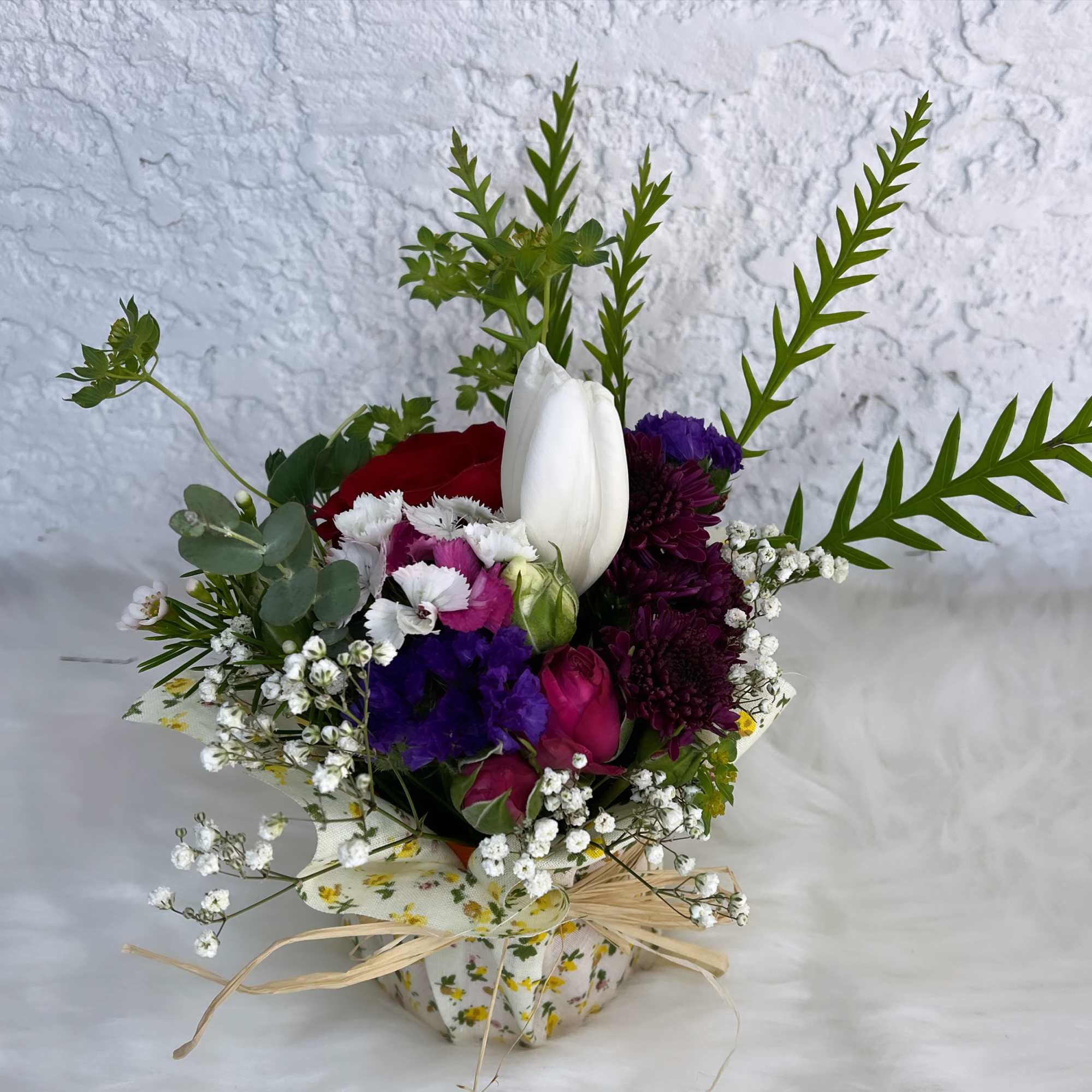 Mixed bouquet with white tulip, red rose, and purple blooms in a floral wrap