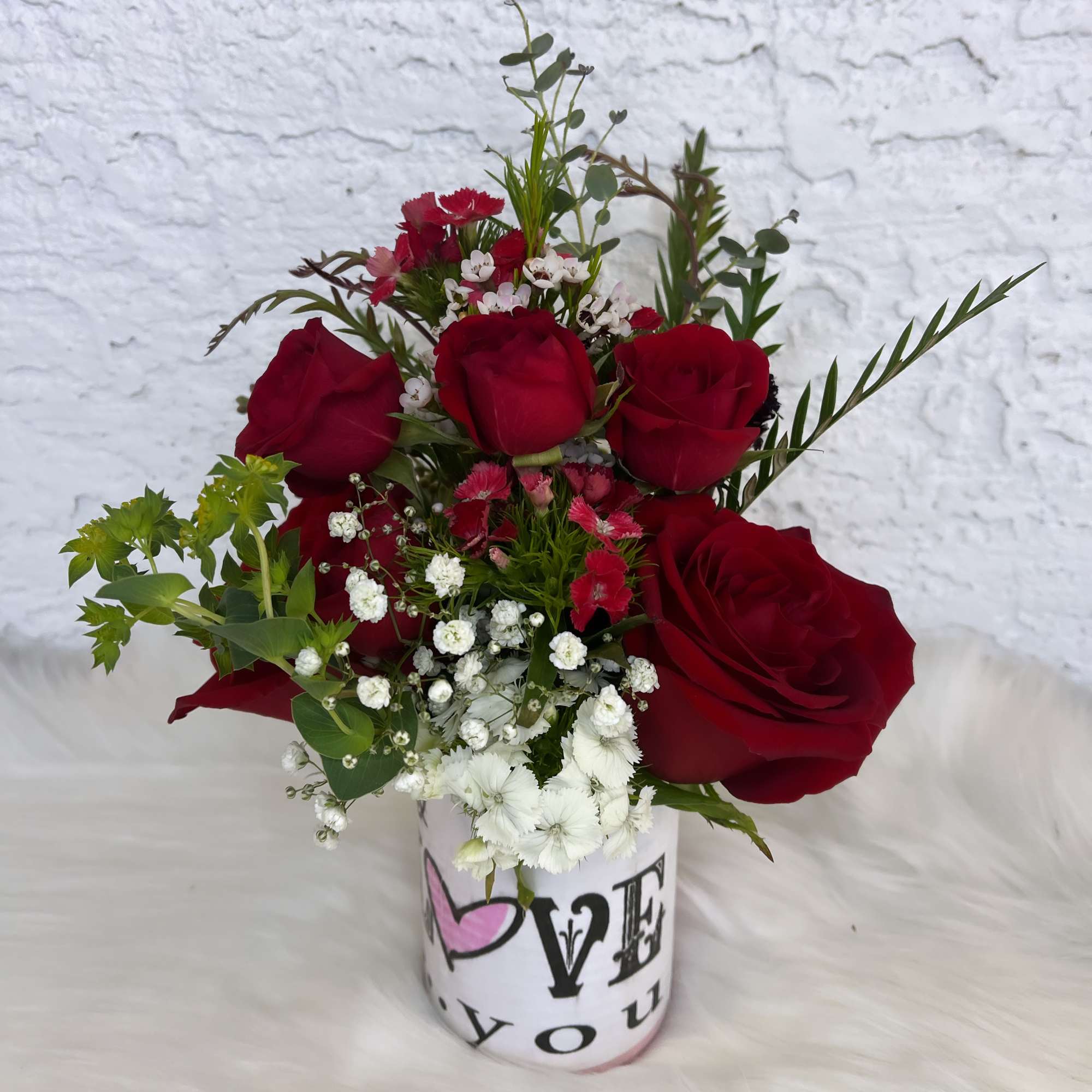 Red roses and white filler flowers in a printed vase