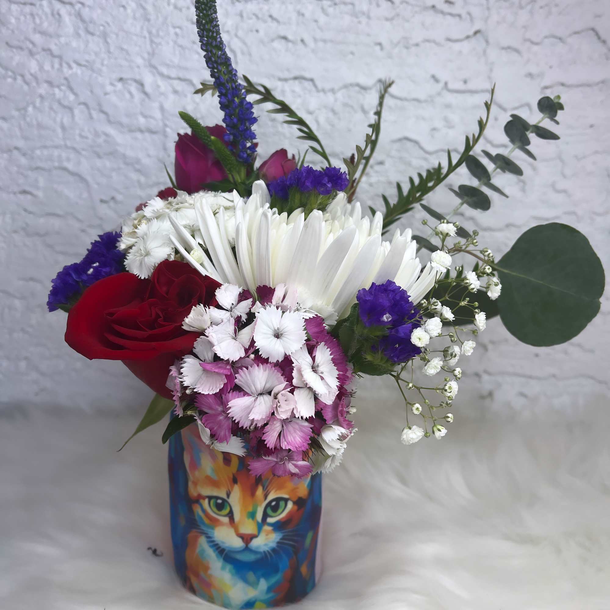 Mixed bouquet in a colorful cat-print vase with red and white flowers