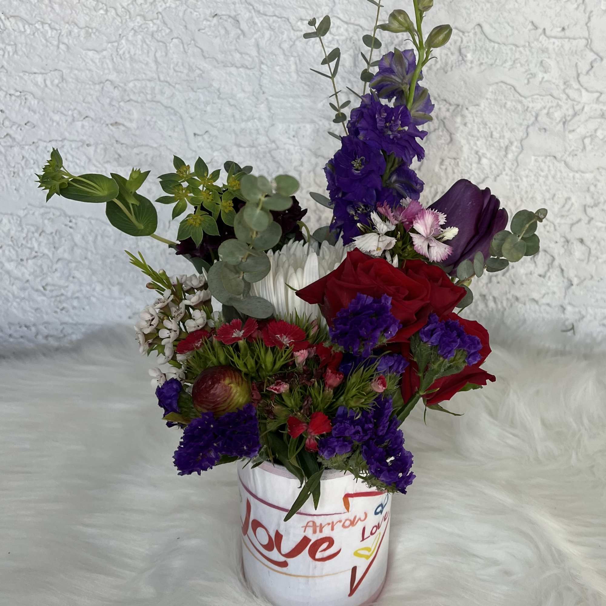 Mixed bouquet in a white vase with red roses and purple flowers