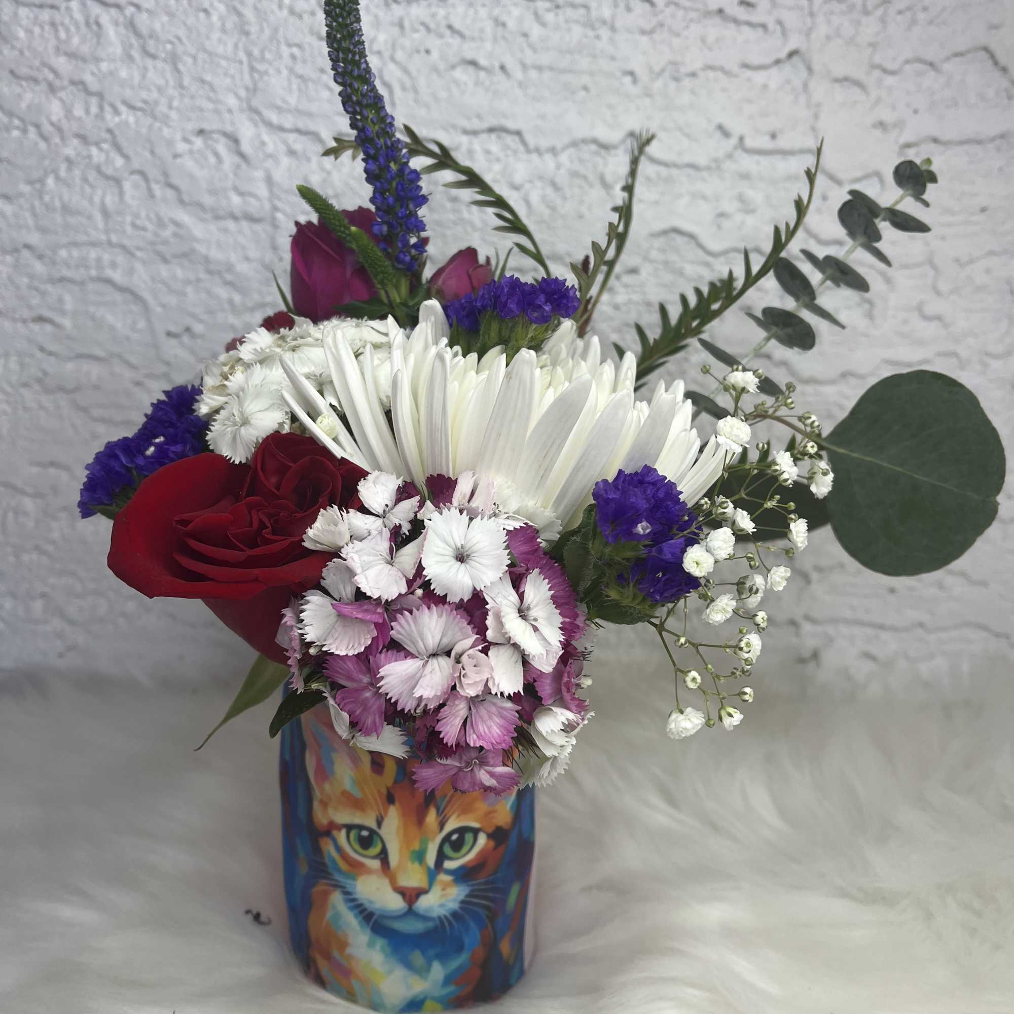 Mixed bouquet in a colorful cat-print vase with red, white, pink, and purple flowers