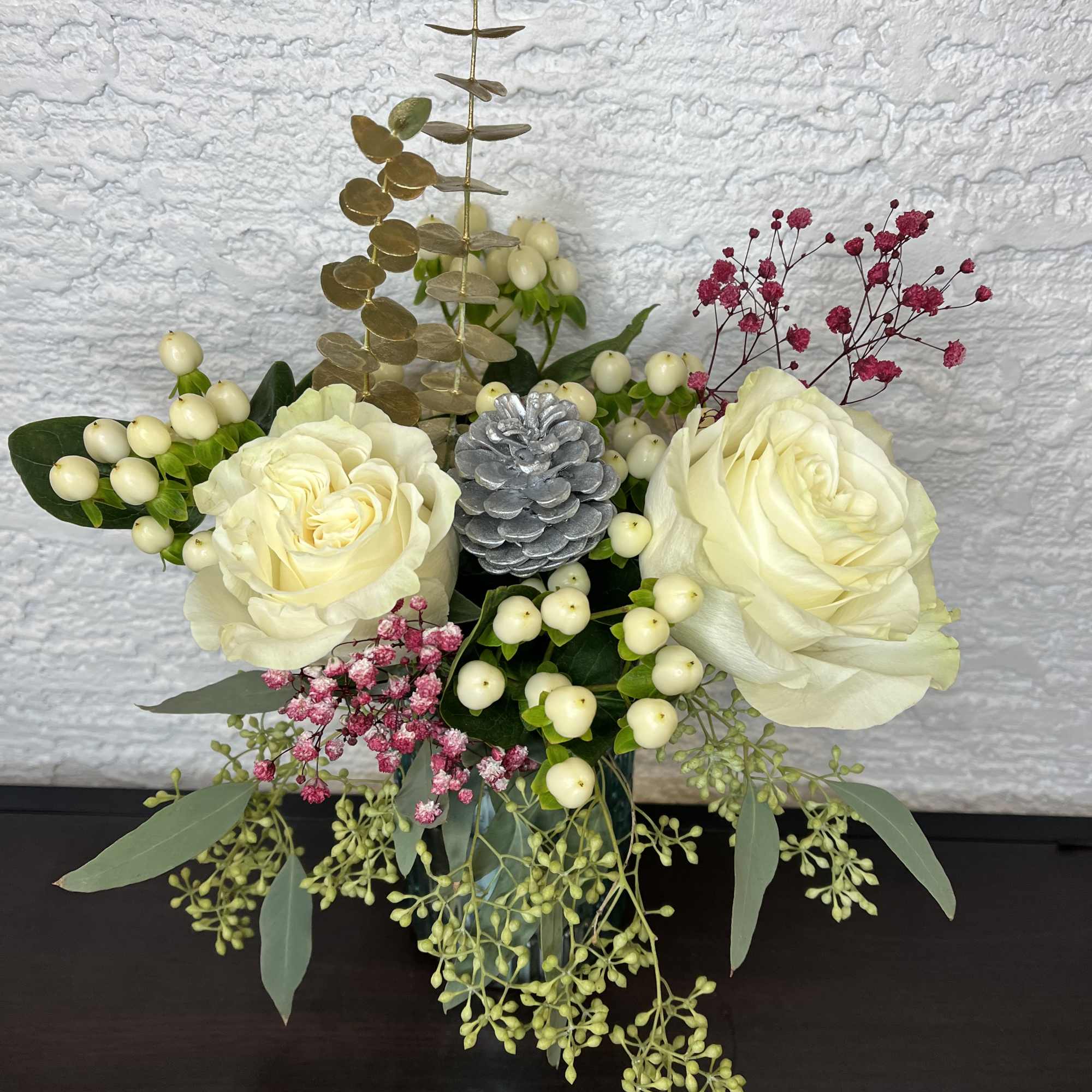 Cream rose arrangement with berries and eucalyptus in a vase