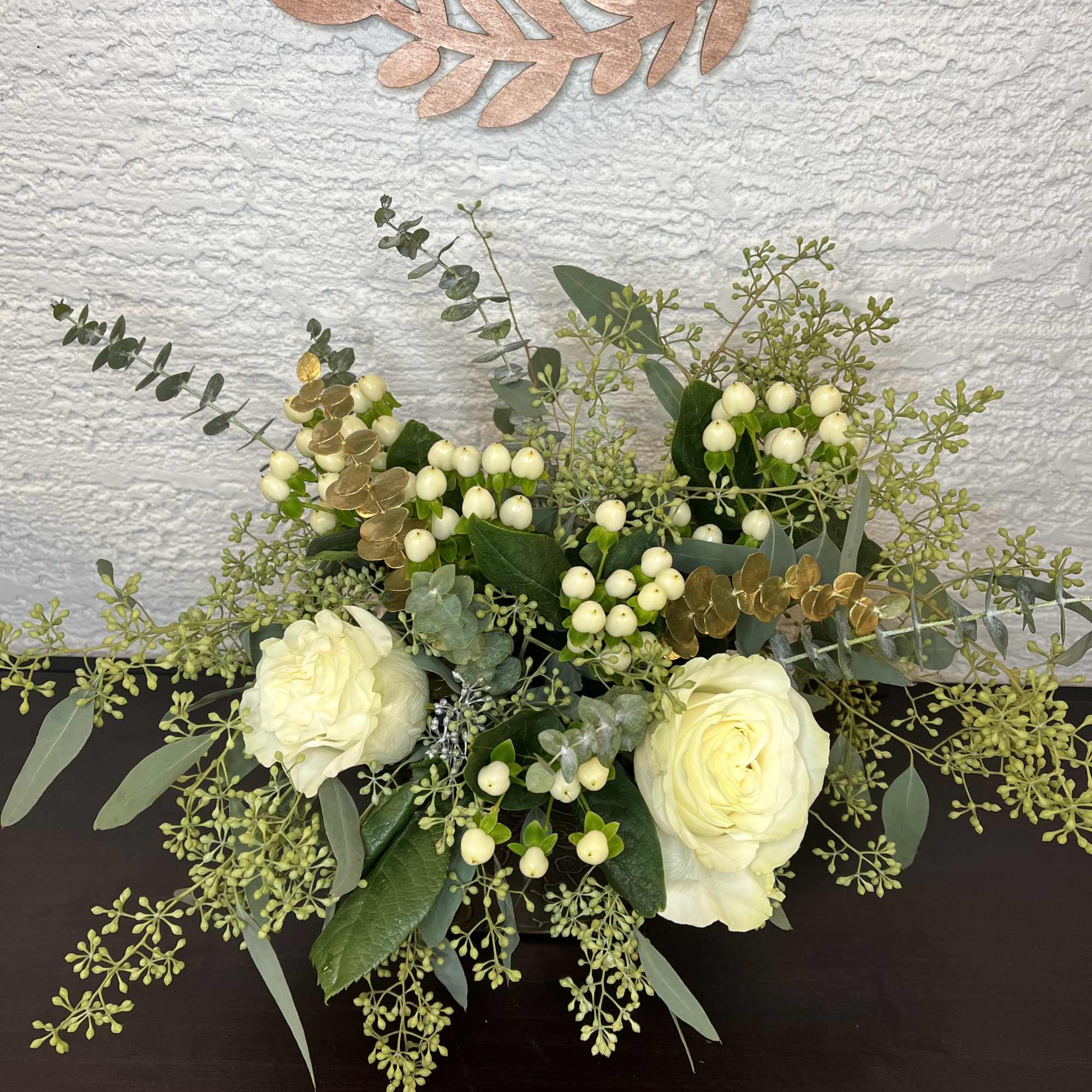White roses with berries and eucalyptus in a low arrangement