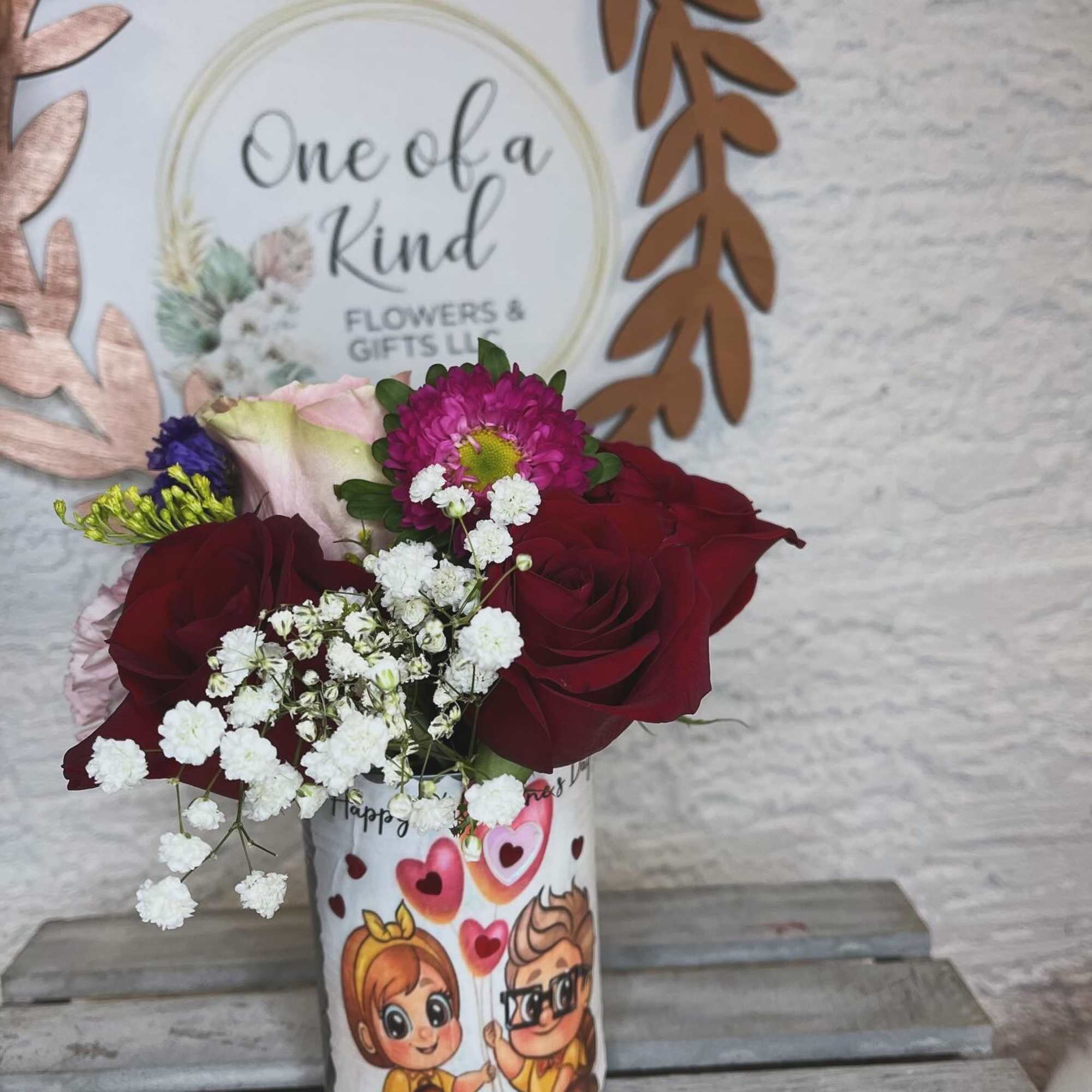 Bouquet of red roses and pink flowers in a printed gift cup