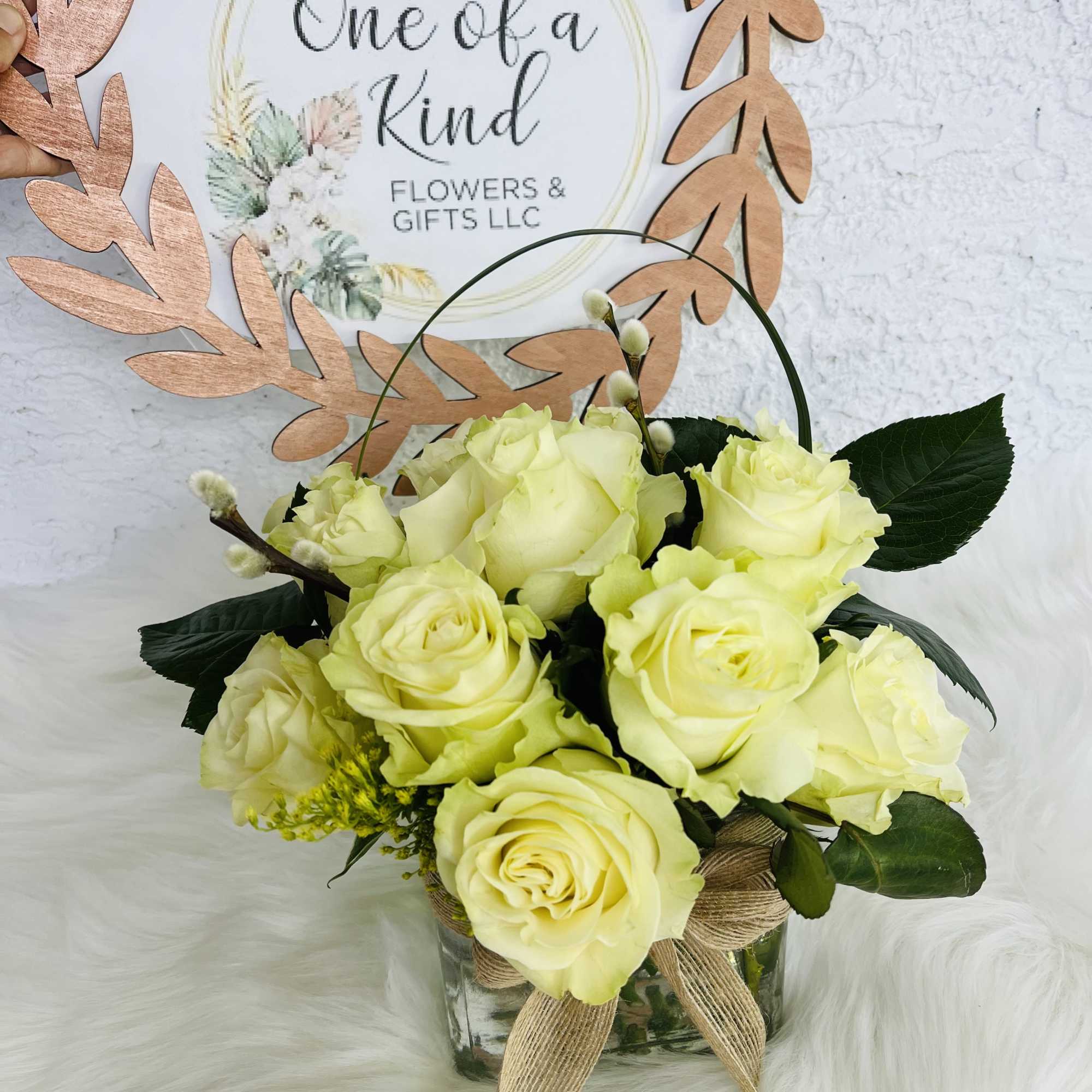 Pale yellow roses in a glass vase with a burlap bow