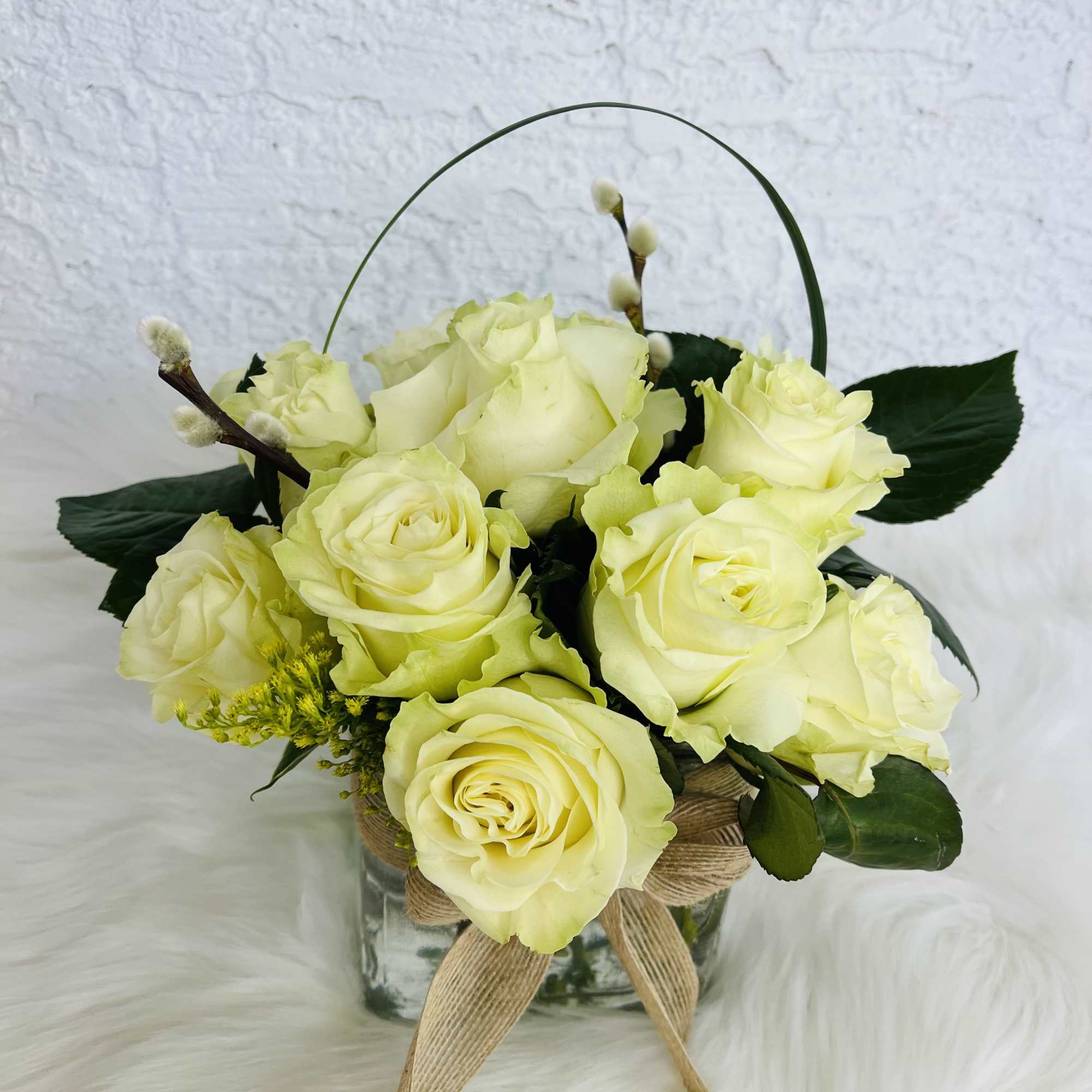 Bouquet of pale yellow roses in a glass vase with a ribbon bow