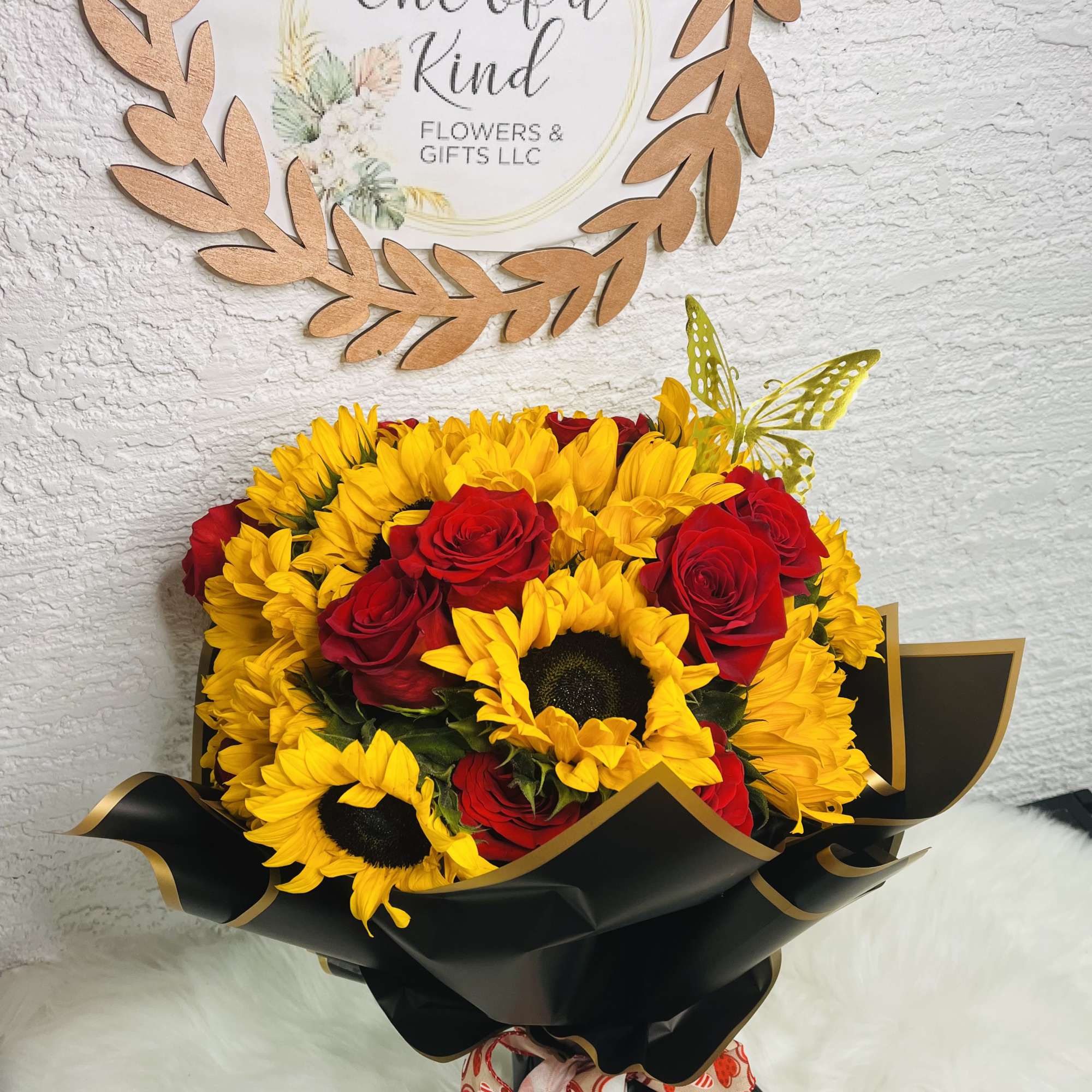 Bouquet of yellow sunflowers and red roses wrapped in black paper