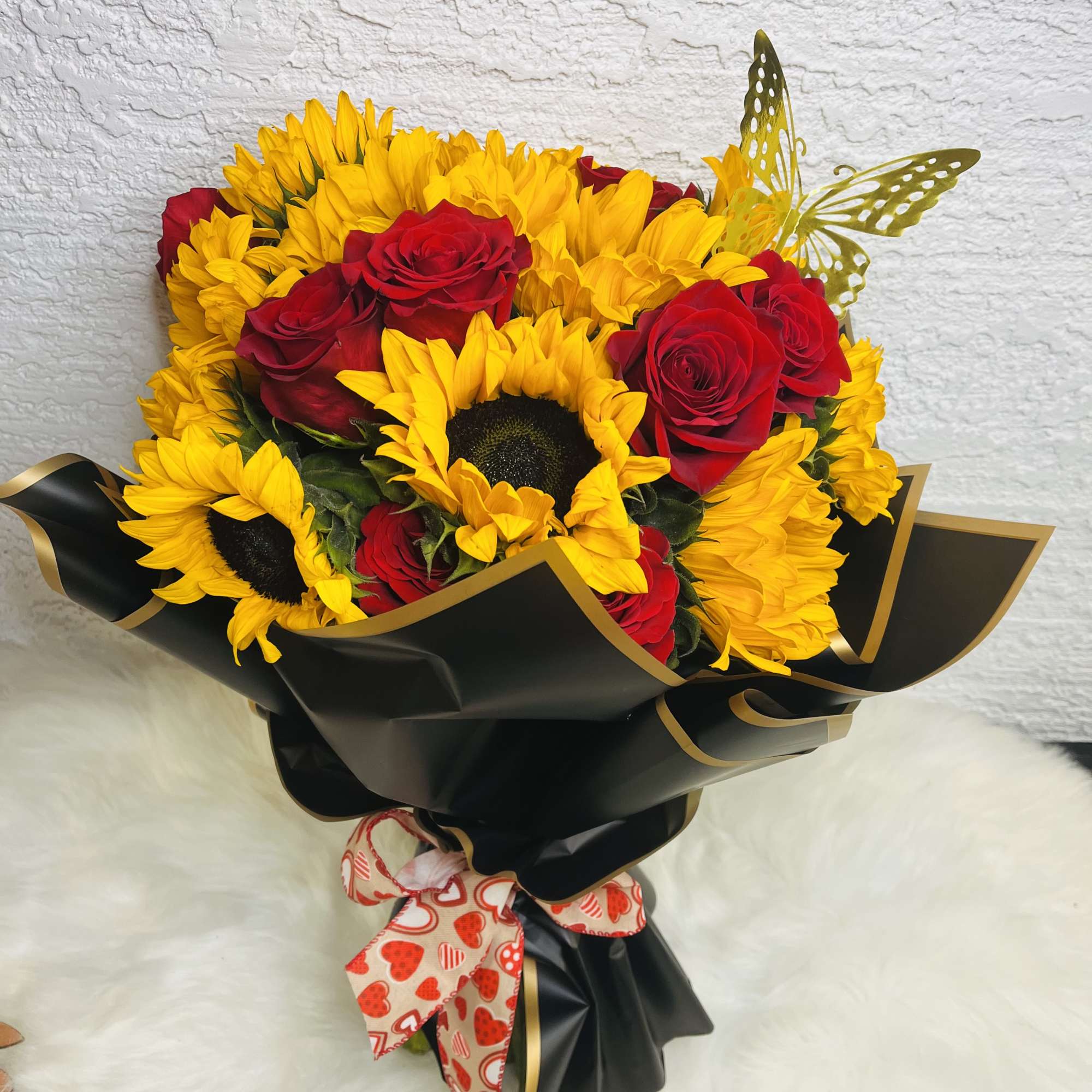 Bouquet of red roses and yellow sunflowers wrapped in black paper